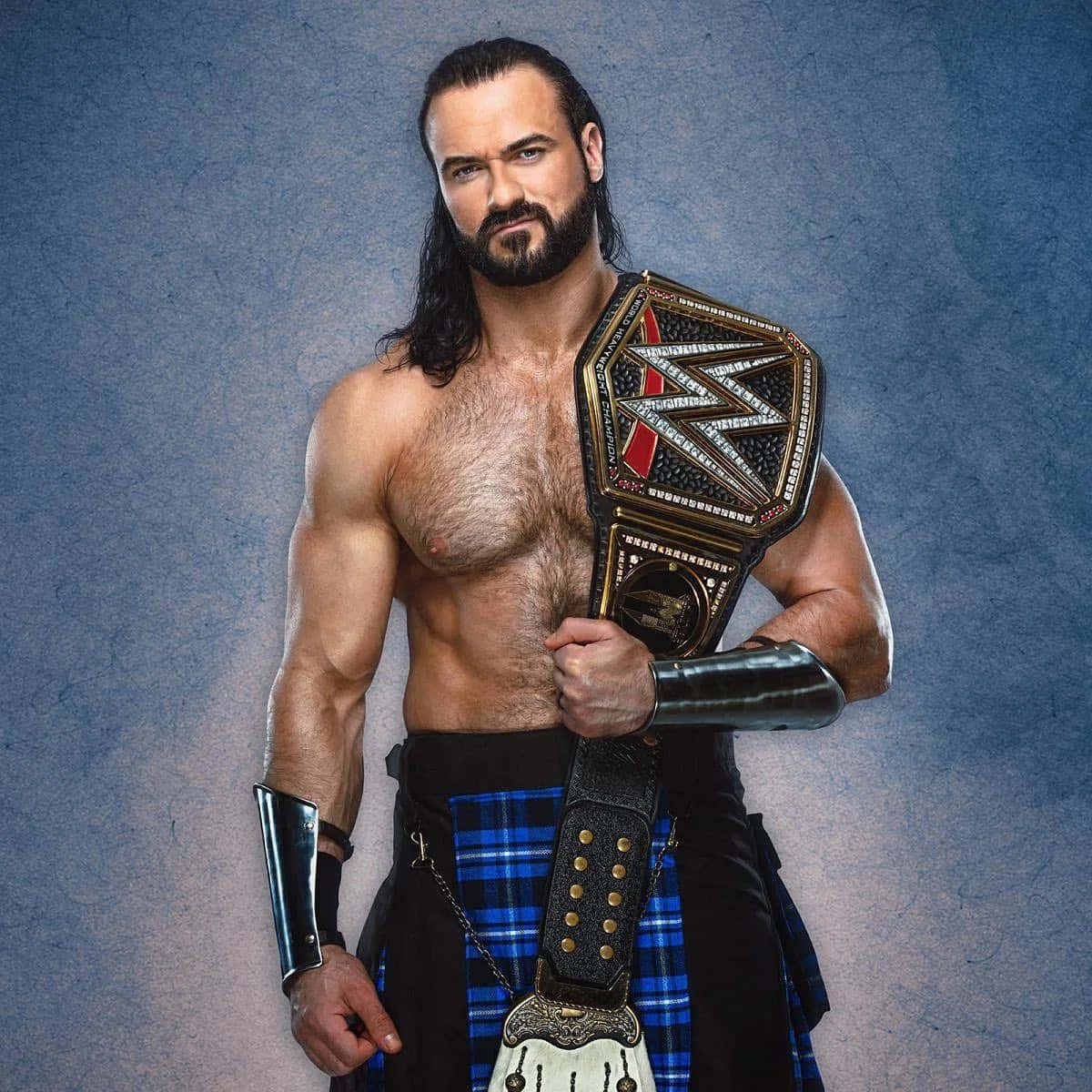 WWE 桌布 壁紙 — 一位肌肉發達的摔角手，留著長黑髮和鬍鬚，手持冠軍腰帶，身穿藍色格子裙，背景為有紋理的藍色。