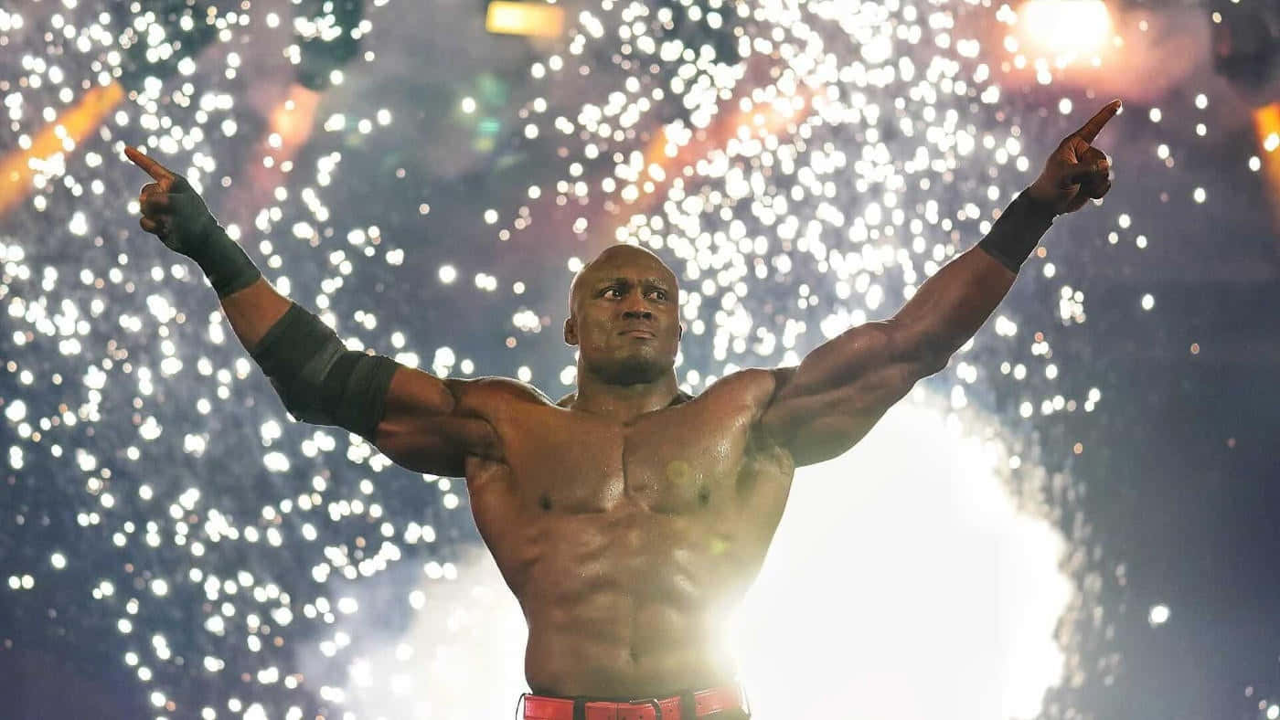 Fight 桌布 壁紙 — 一位肌肉發達的摔角手勝利地高舉雙臂，兩隻食指指向上方，背後明亮的舞台燈光和火花爆炸開來。