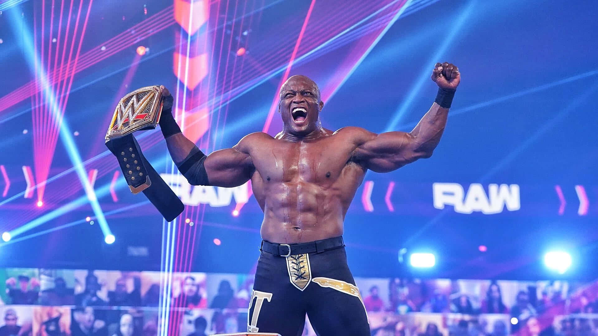 Fight 桌布 壁紙 — 一位肌肉發達的摔角手在WWE RAW活動中，在充滿活力的舞台燈光下勝利地舉起冠軍腰帶和拳頭。
