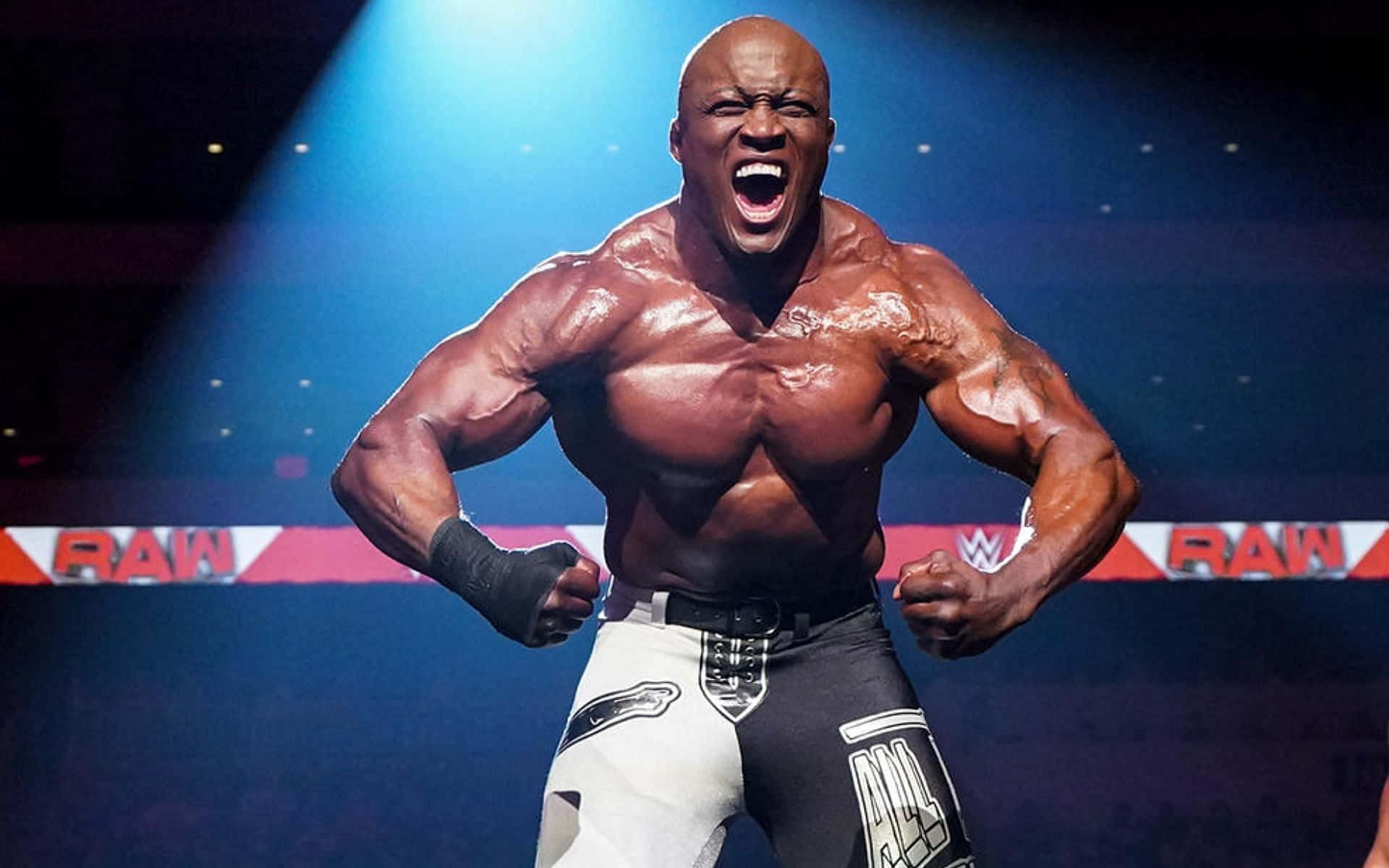 Fight 桌布 壁紙 — 一位肌肉發達的摔角手在WWE RAW舞台上，在藍色燈光照射下，於聚光燈下勝利地咆哮。