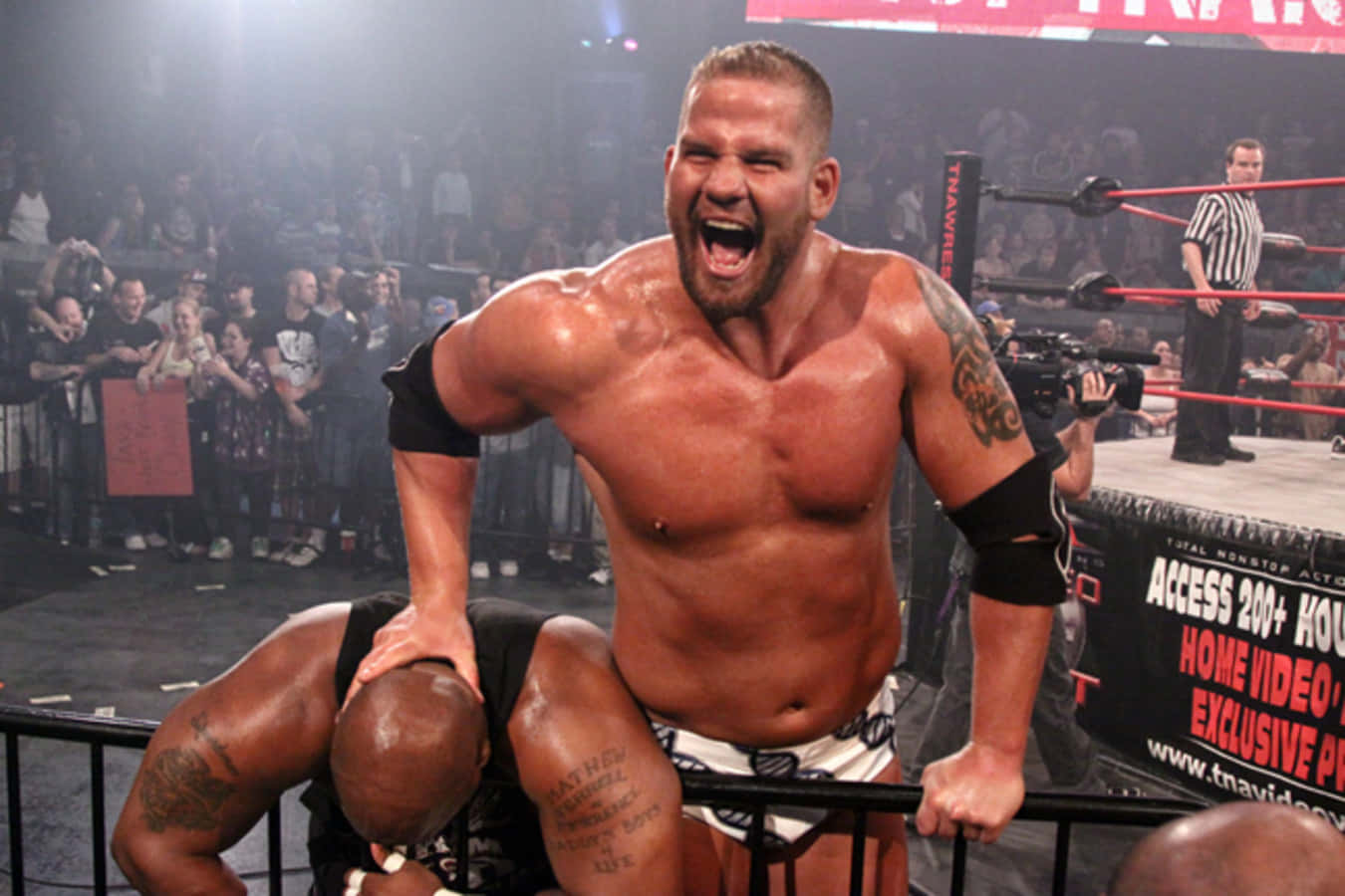 actor 桌布 壁紙 — 一位肌肉發達的摔角手在明亮的場館燈光下，於WWE賽事中壓制對手並發出勝利的怒吼。