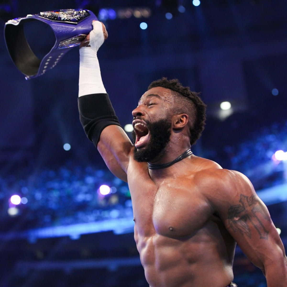 WWE 桌布 壁紙 — 一位肌肉發達的摔角手在燈光明亮的競技場中，勝利地將紫色冠軍腰帶高舉過頭。