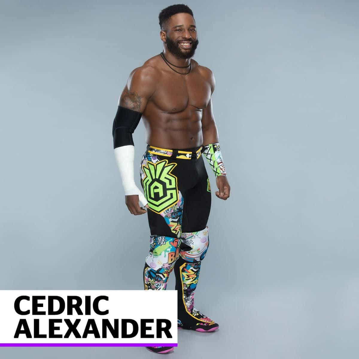WWE 桌布 壁紙 — 一位肌肉發達的摔角手穿著鮮豔的漫畫風格短褲，在樸素的灰色工作室背景前自信地微笑。