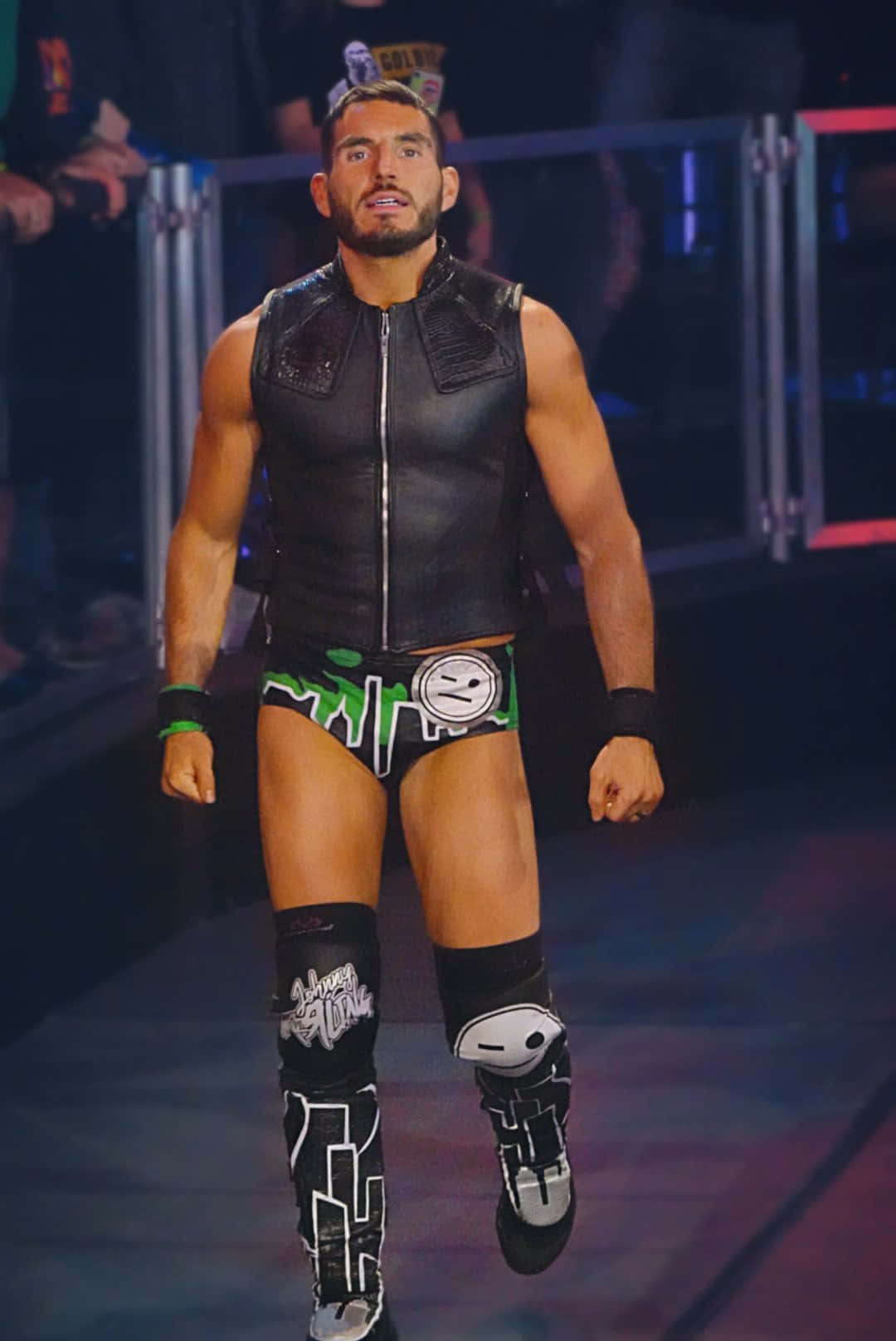 WWE 桌布 壁紙 — 一位肌肉發達的摔角手身穿黑色和綠色的裝備，自信地走下燈光明亮的擂台入口坡道。