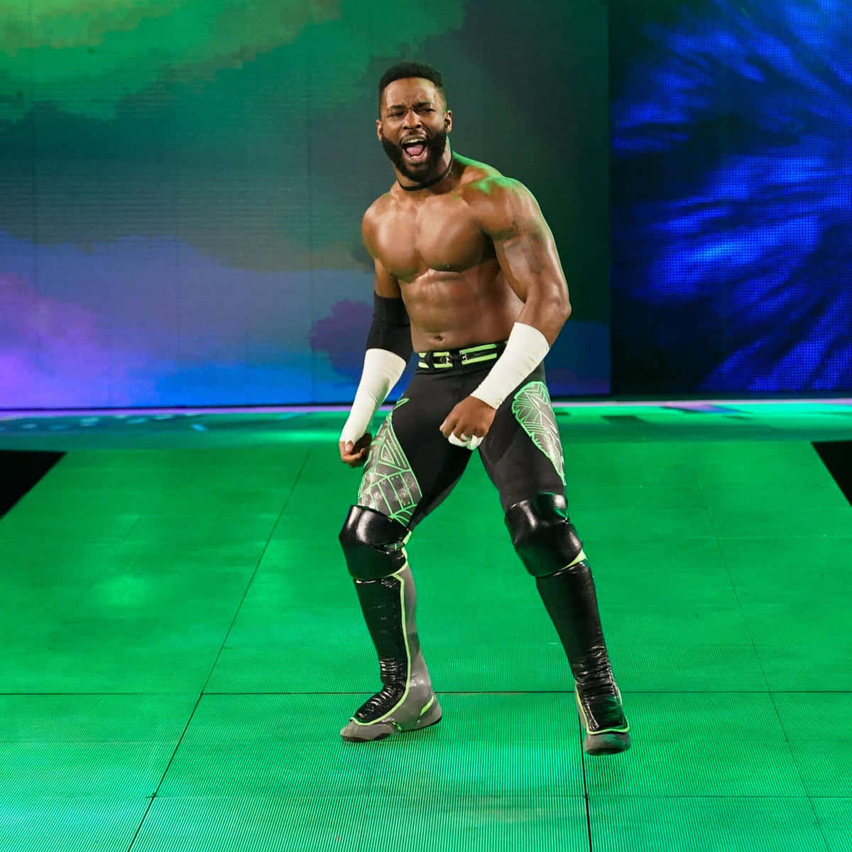 WWE 桌布 壁紙 — 一位肌肉發達的摔角手身穿黑色和綠色裝備，在色彩繽紛的燈光下於充滿活力的綠色舞台上猛烈咆哮。