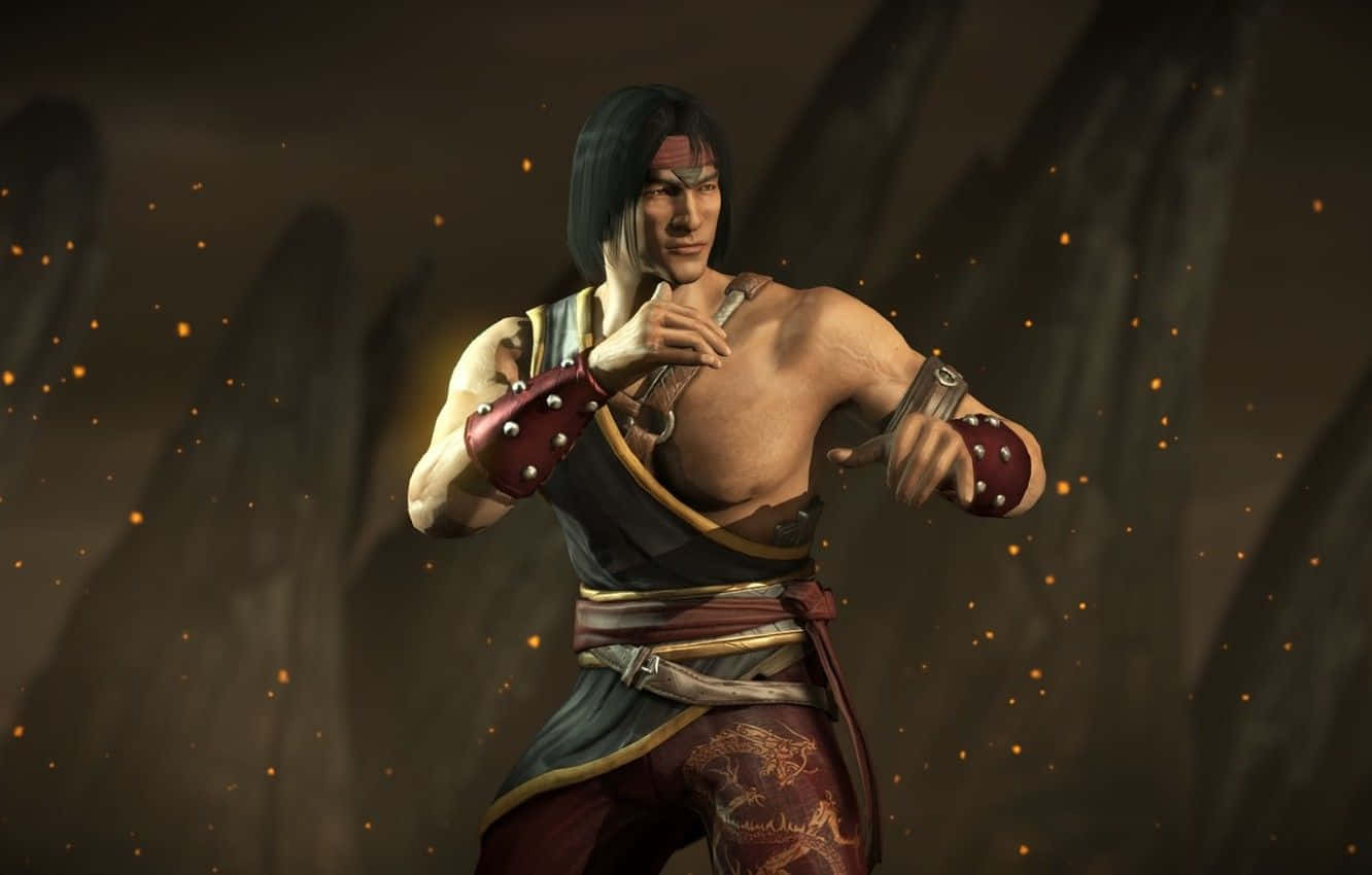 Mortal Kombat Liu Kang 桌布 壁紙 — 一位肌肉發達的武術家身穿紅色和金色盔甲，在黑暗岩石背景下，於漂浮的餘燼中擺出戰鬥姿勢。