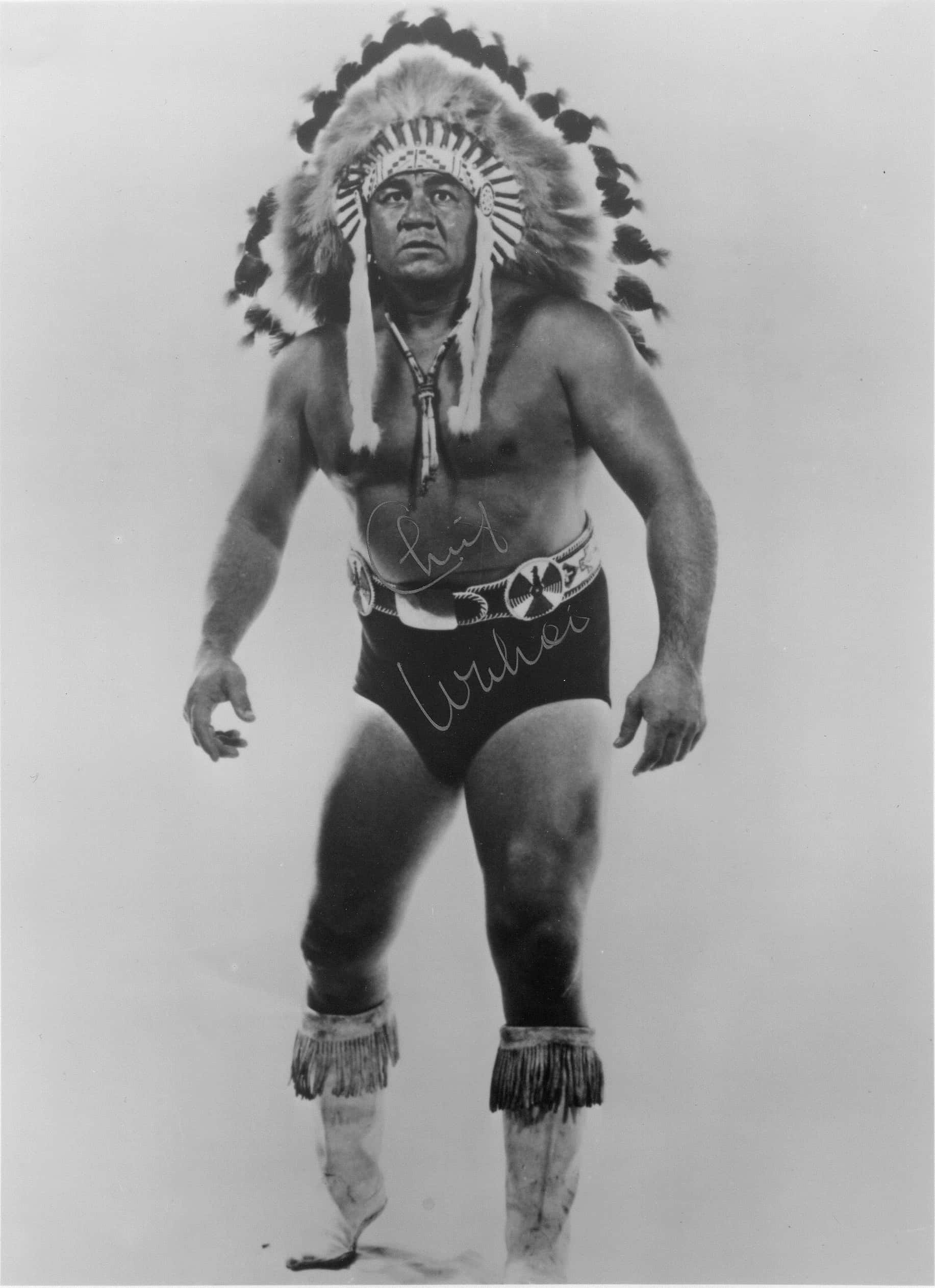 Native American 桌布 壁紙 — 一位肌肉發達的男子，戴著羽毛頭飾和流蘇短褲，在工作室肖像中自信地站立。