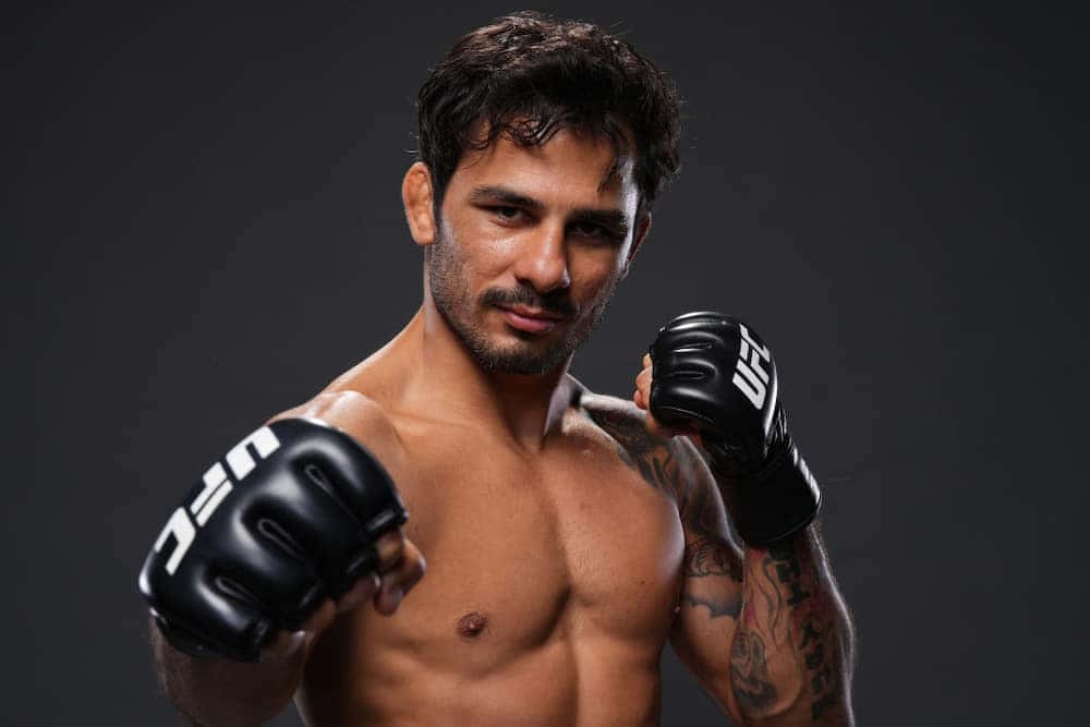 UFC 桌布 壁紙 — 一位肌肉發達的男性拳手戴著黑色UFC手套，在黑暗的攝影棚背景下凝視著。
