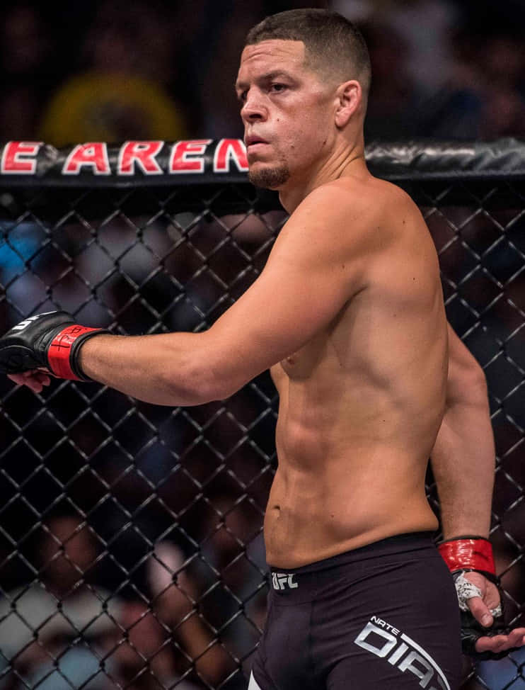 UFC 桌布 壁紙 — 一位肌肉發達的男性拳手穿著黑色短褲和紅色手套，帶著專注的強度站在UFC八角籠內。