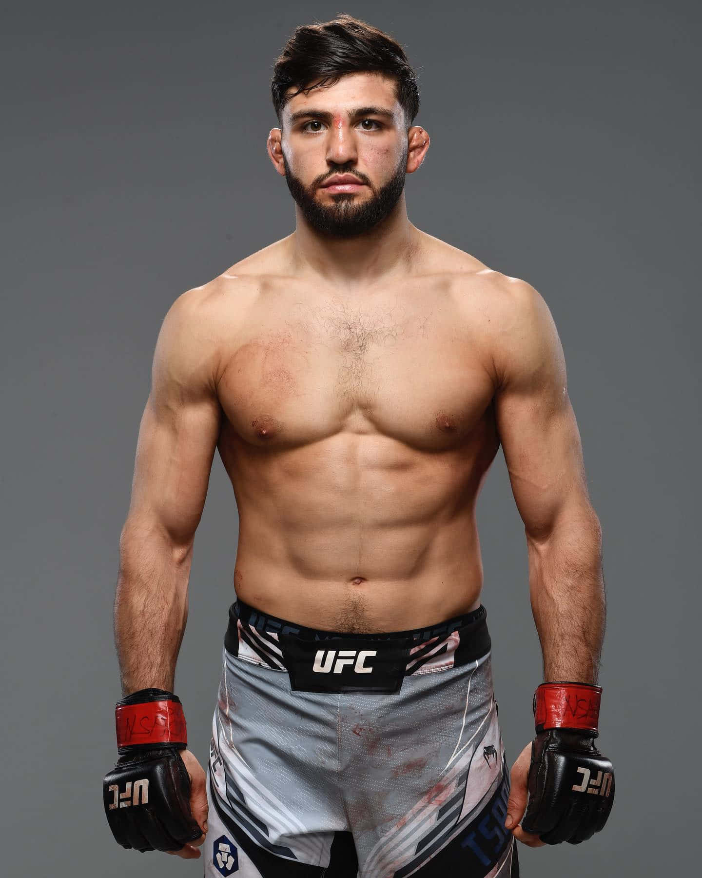 UFC 桌布 壁紙 — 一位肌肉發達的男性綜合格鬥選手身穿UFC裝備，自信地站在純灰色背景前。