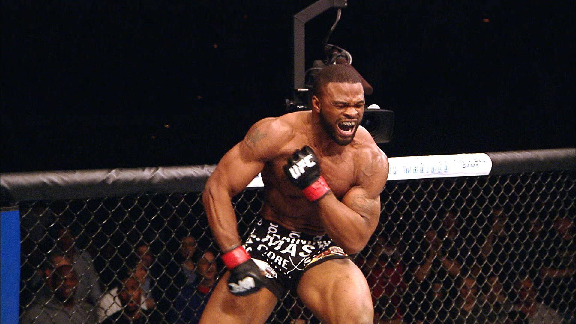 Tyron Woodley 桌布 壁紙 — 一位肌肉發達的鬥士在UFC八角籠內勝利咆哮，背景有觀眾觀看。