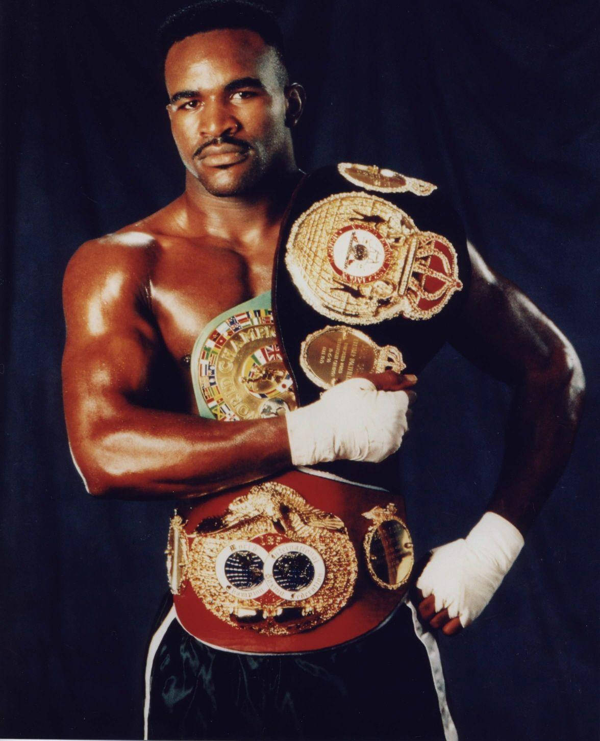 Boxing 桌布 壁紙 — 一位肌肉發達的黑人拳擊手自信地站在黑暗背景前，自豪地展示腰間和手臂上的多條冠軍腰帶。