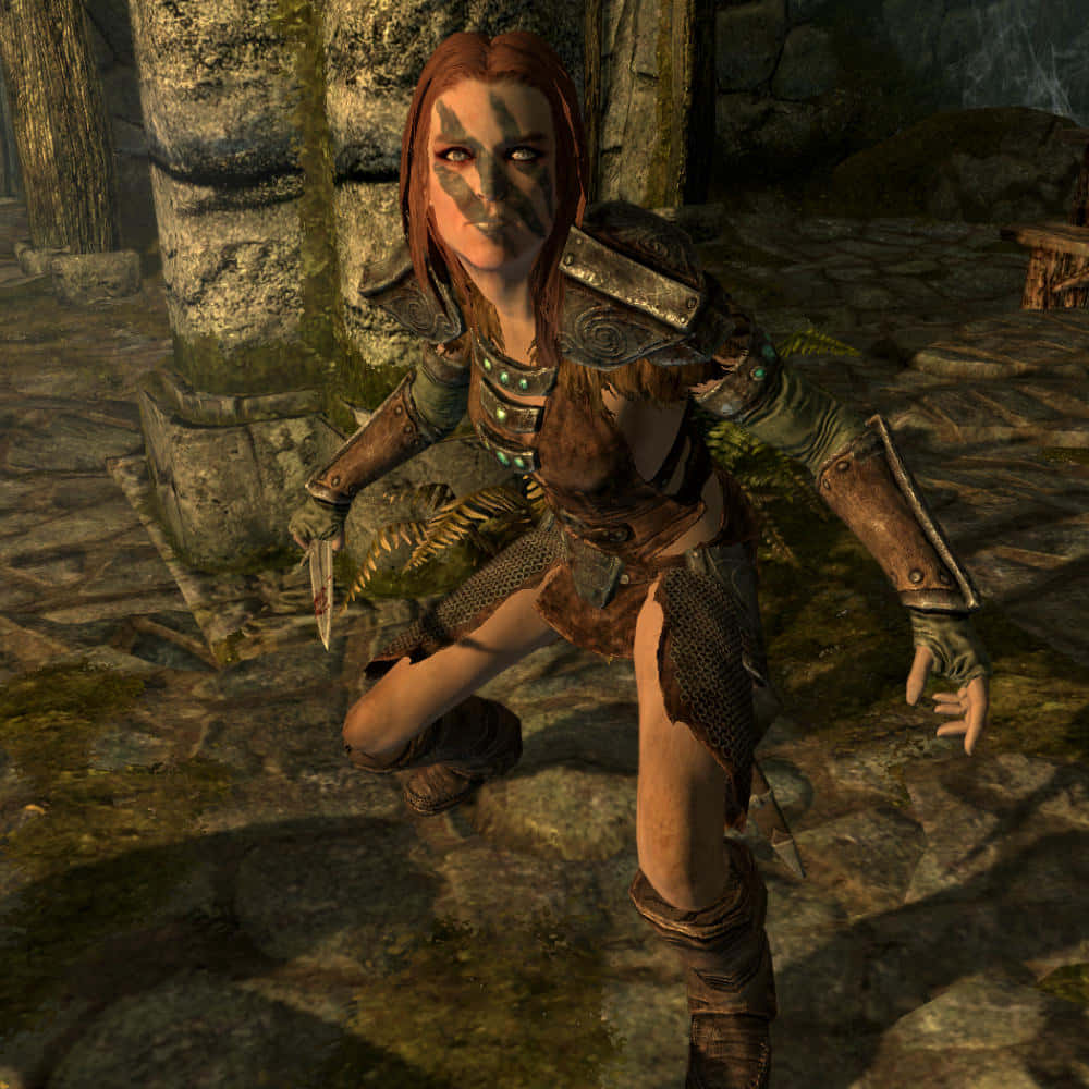 Aela The Huntress 桌布 壁紙 — 一位臉上塗有顏料的女戰士蹲在長滿苔蘚的石頭廢墟中，手持匕首。