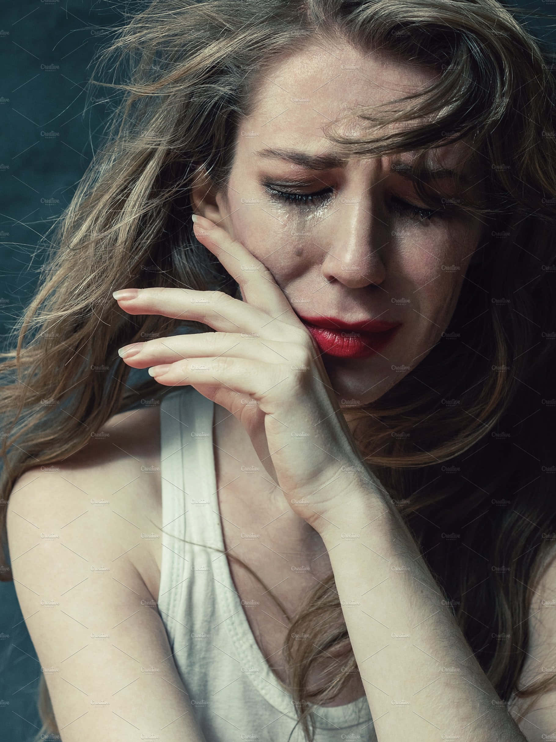 cry 桌布 壁紙 — 一位臉上帶有淚痕、紅唇的女性，輕輕將臉頰貼在深藍綠色背景上。