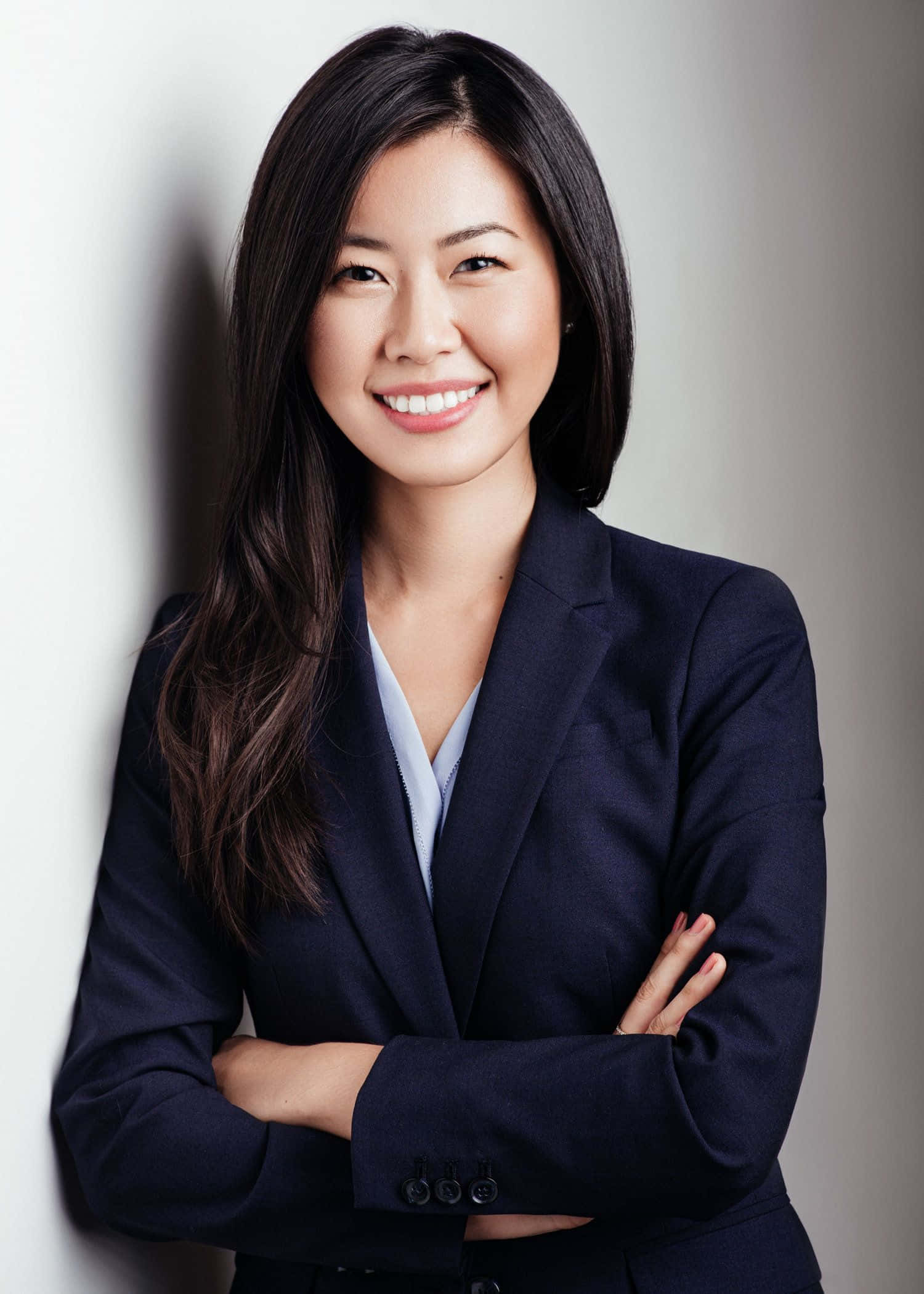 Asian Woman 桌布 壁紙 — 一位自信的亞洲女商人交叉雙臂，對著白色牆壁微笑，專業工作室肖像。
