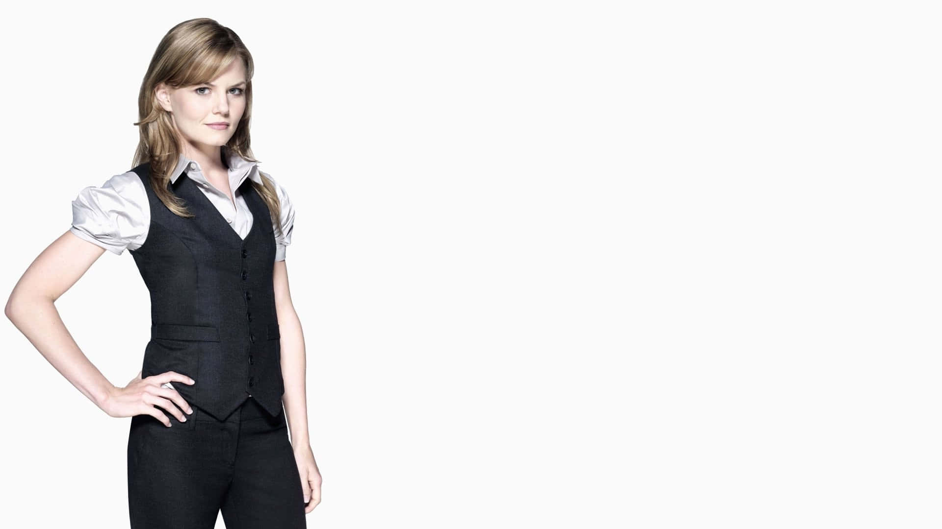 jennifer morrison 桌布 壁紙 — 一位自信的女性，身穿黑色背心和白色襯衫，一手叉腰，站在純白背景前。