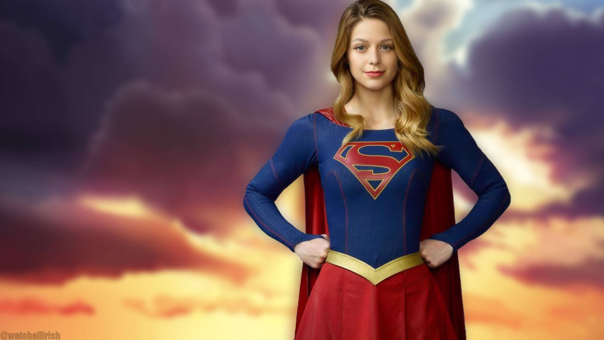 Superwoman 桌布 壁紙 — 一位自信的女超級英雄身穿藍色和紅色套裝，站在紫色和橙色雲彩的戲劇性日落天空前。