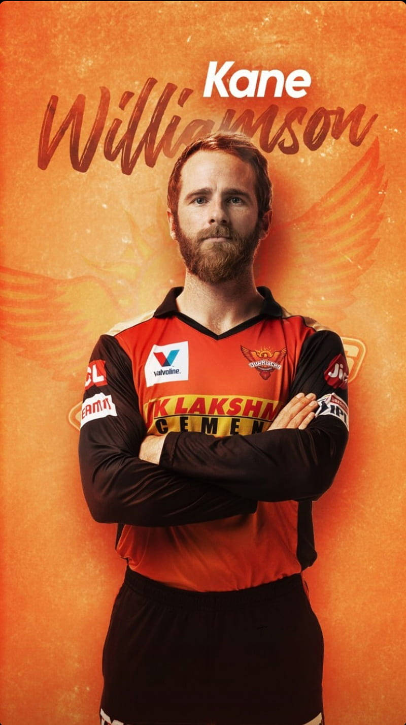 Sunrisers Hyderabad 桌布 壁紙 — 一位自信的板球運動員雙臂交叉，站在火熱的橙色背景前，他的名字寫在上方。