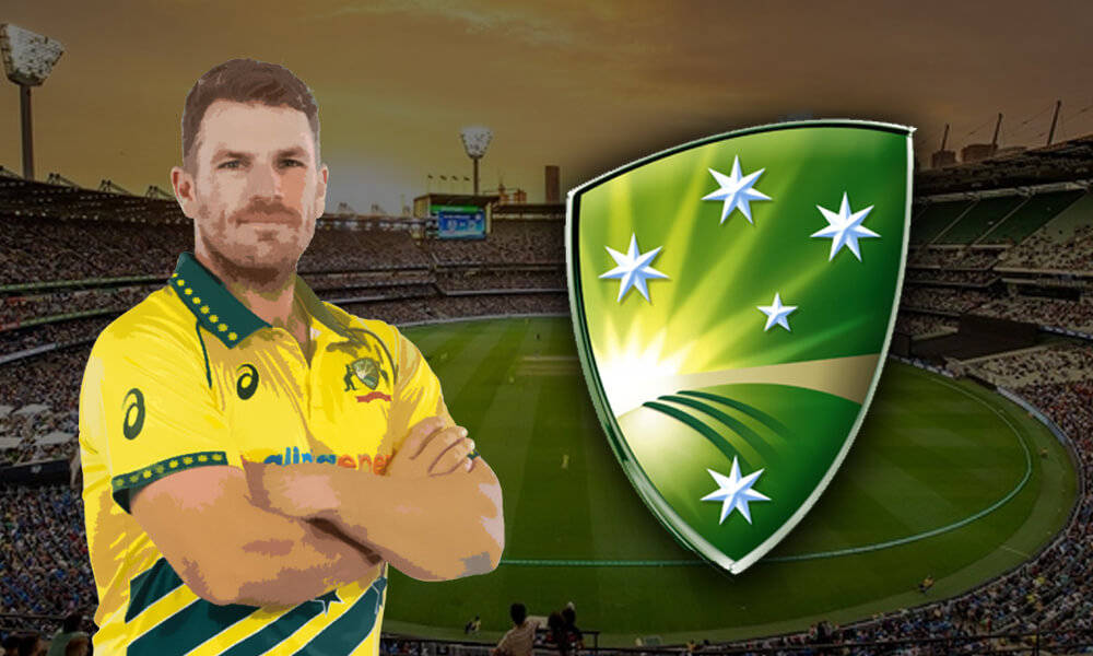 Aaron Finch 桌布 壁紙 — 一位自信的澳洲板球運動員身穿黃色球衣，雙臂交叉站在體育場背景前，綠色和金色的球隊徽章在他旁邊閃耀。