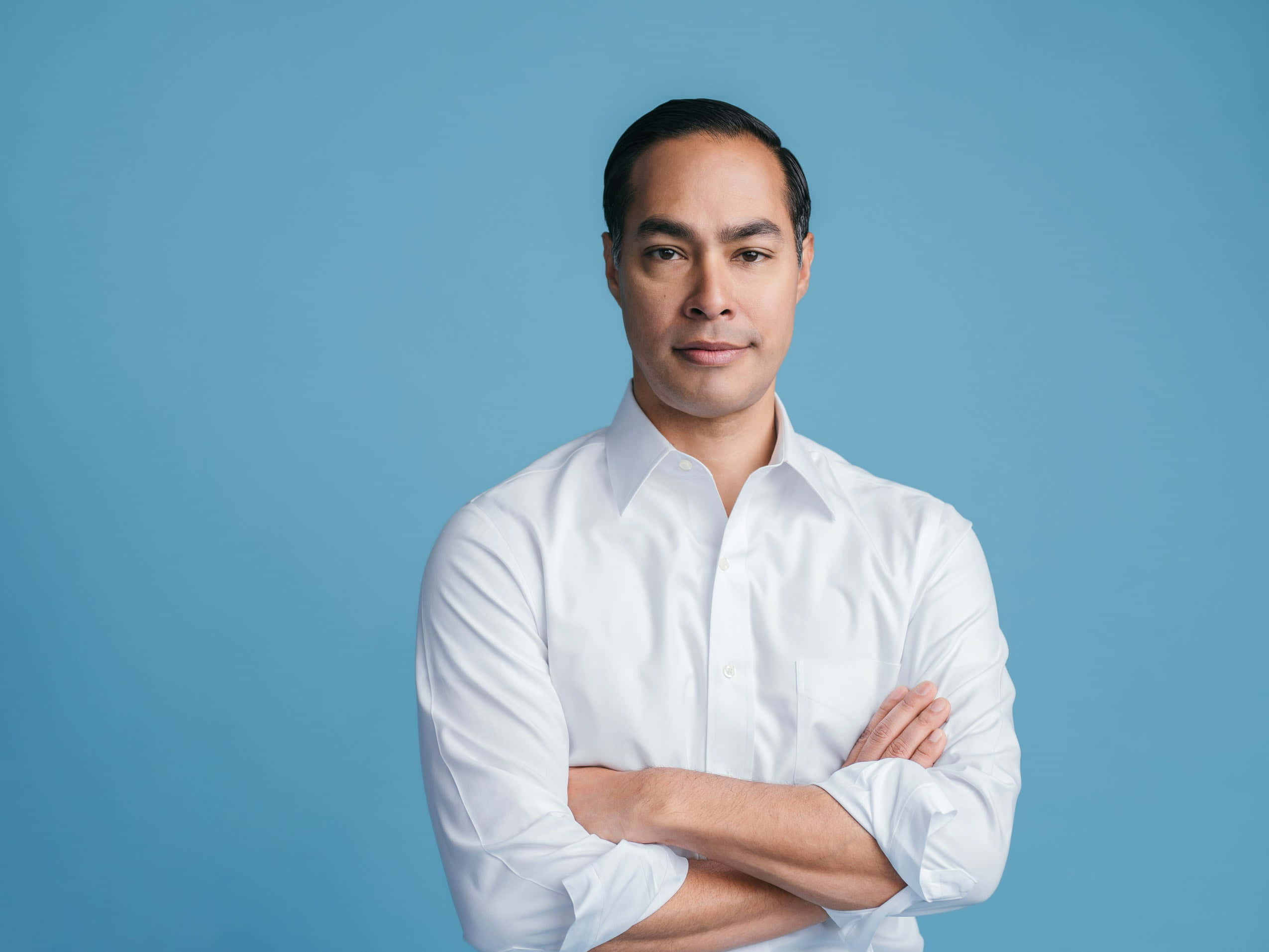 Celebrity 桌布 壁紙 — 一位自信的男人穿著一件清爽的白襯衫，雙手交叉站在純藍色的攝影棚背景前。