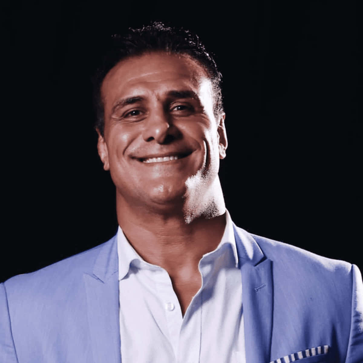 WWE 桌布 壁紙 — 一位自信的男人穿著淺藍色西裝，在純黑背景前溫暖地微笑。