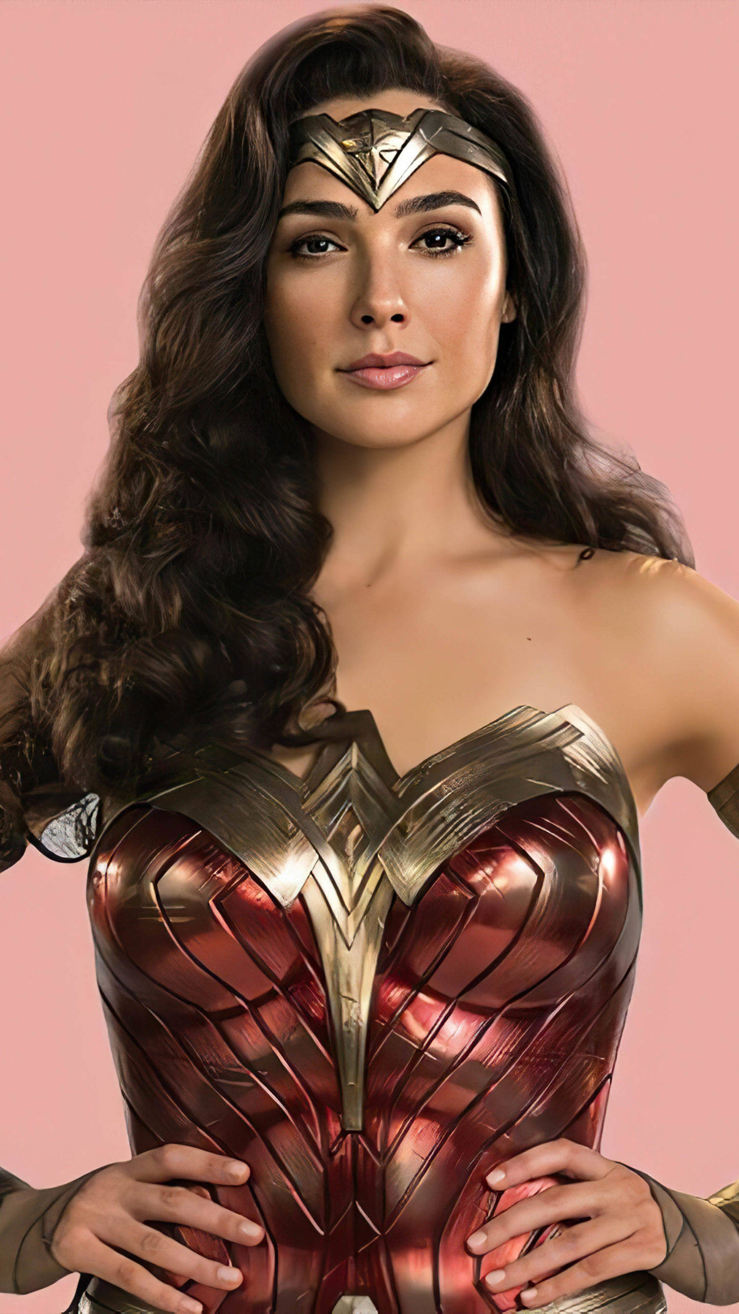 Wonder Woman 桌布 壁紙 — 一位自信的神力女超人穿著她標誌性的紅色和金色盔甲，在柔和的粉紅色背景前擺姿勢。