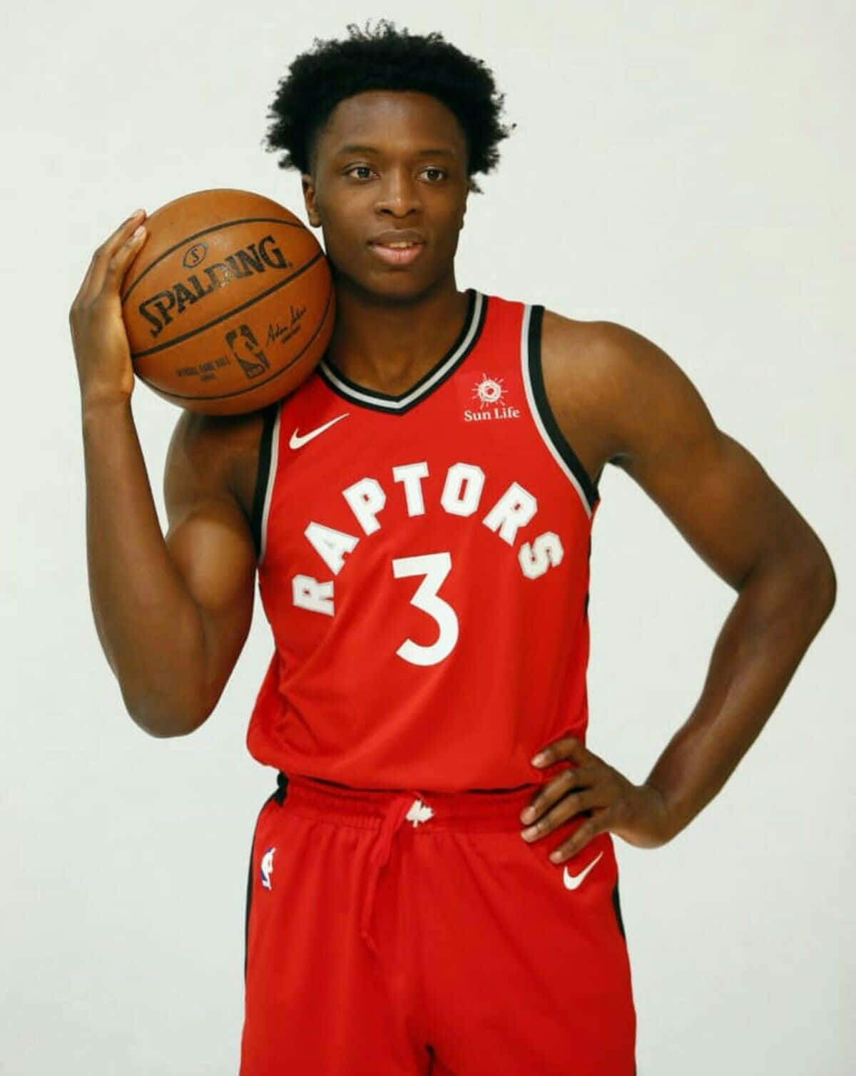 NBA 桌布 壁紙 — 一位自信的籃球運動員穿著紅色Raptors球衣，在白色工作室背景前拿著Spalding籃球。