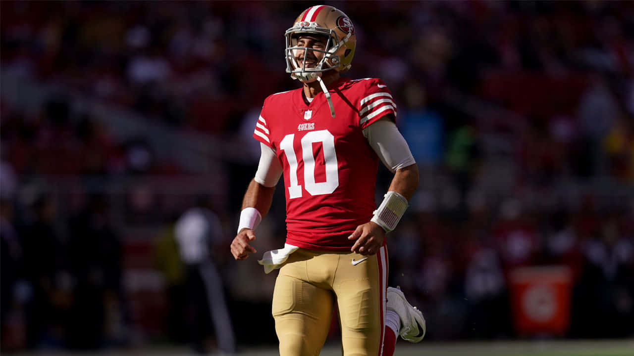 Jimmy Garoppolo 桌布 壁紙 — 一位舊金山四九人隊的四分衛身穿紅金色球衣，在陽光明媚的比賽中自信地微笑。