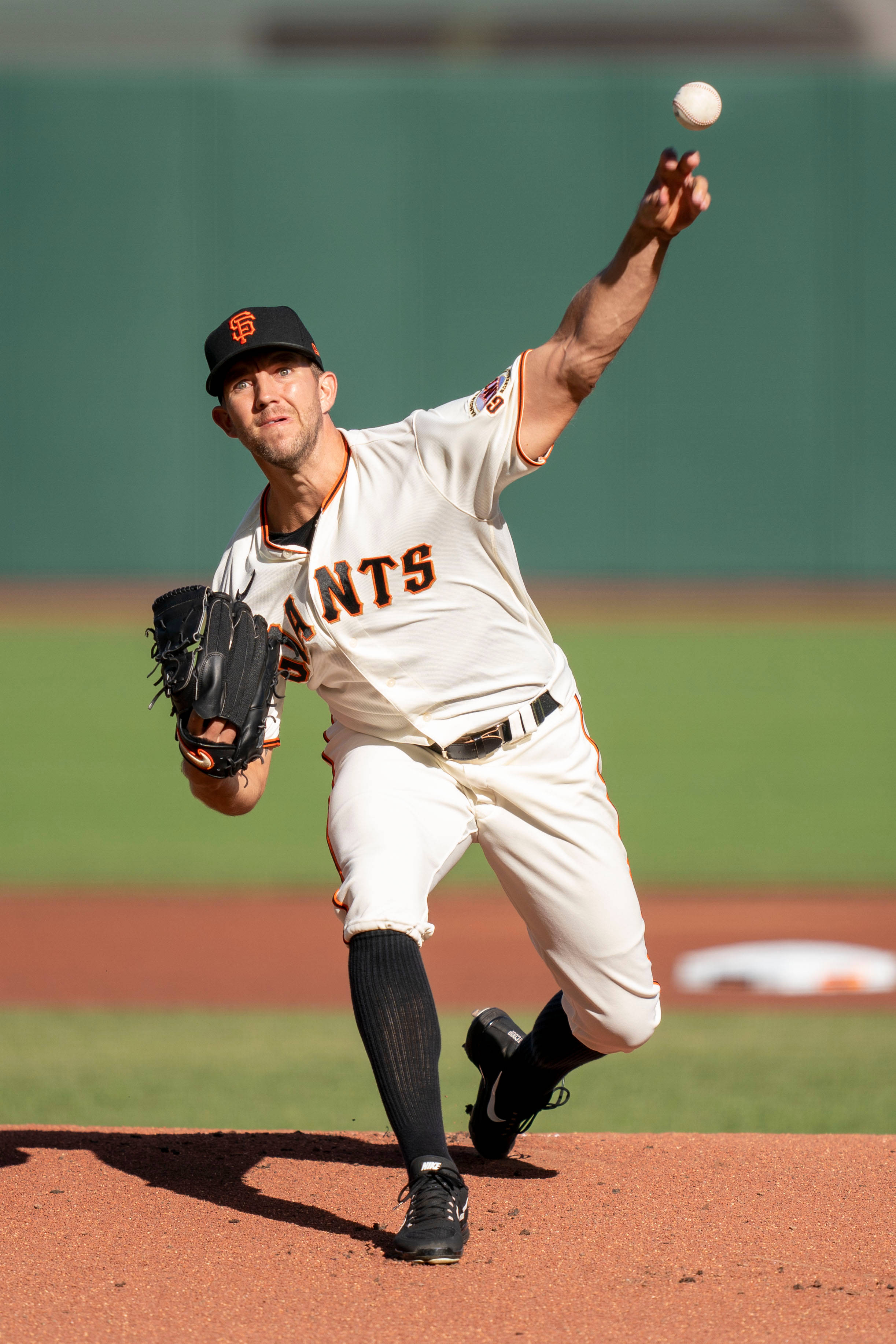 San Francisco Giants 桌布 壁紙 — 一位舊金山巨人隊投手在陽光照耀的棒球投手丘上投球，身後是綠色的外野。