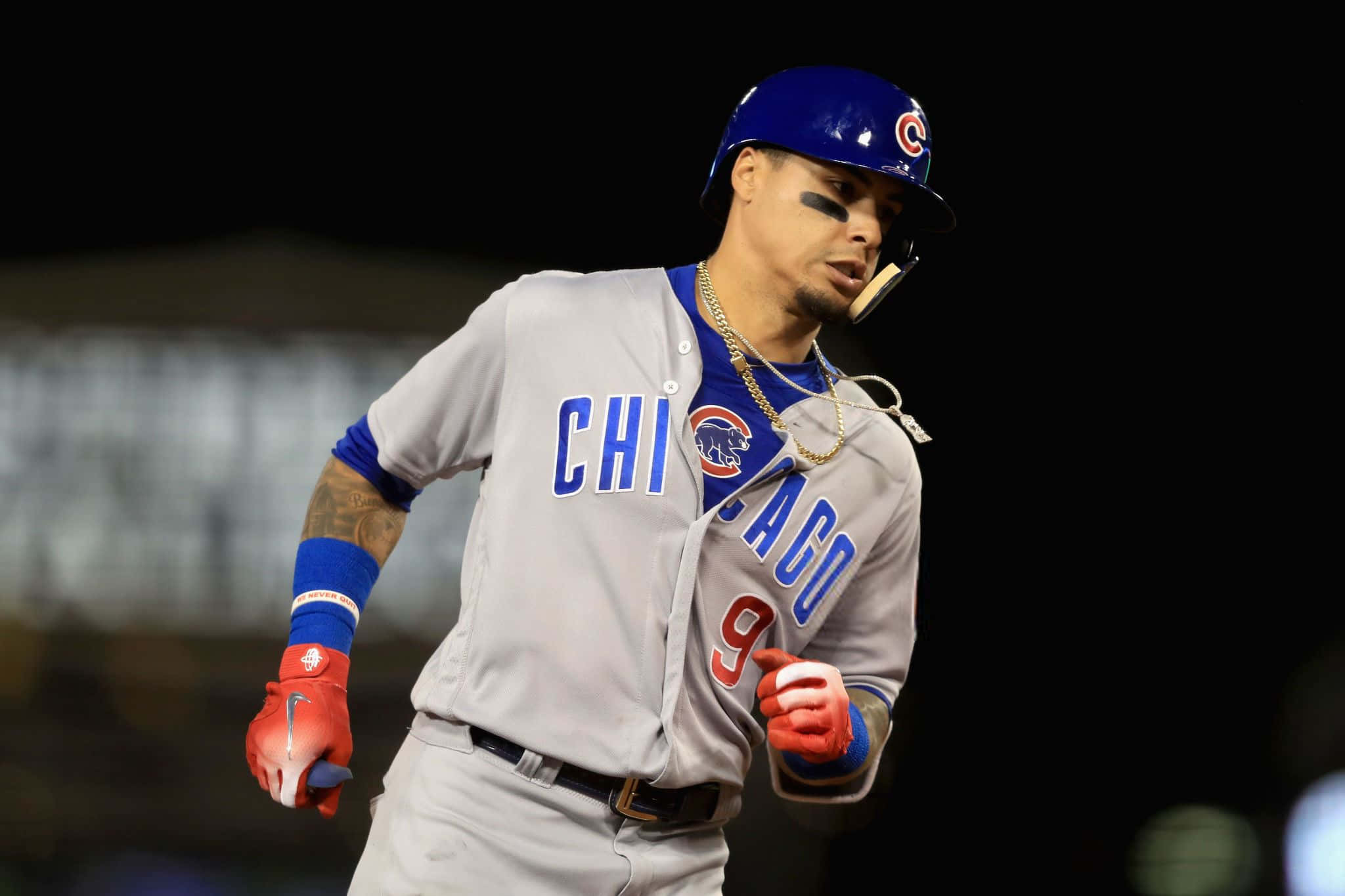 College Baseball 桌布 壁紙 — 一位芝加哥小熊隊棒球選手穿著灰色制服，在夜間球場燈光下專注地奔跑。