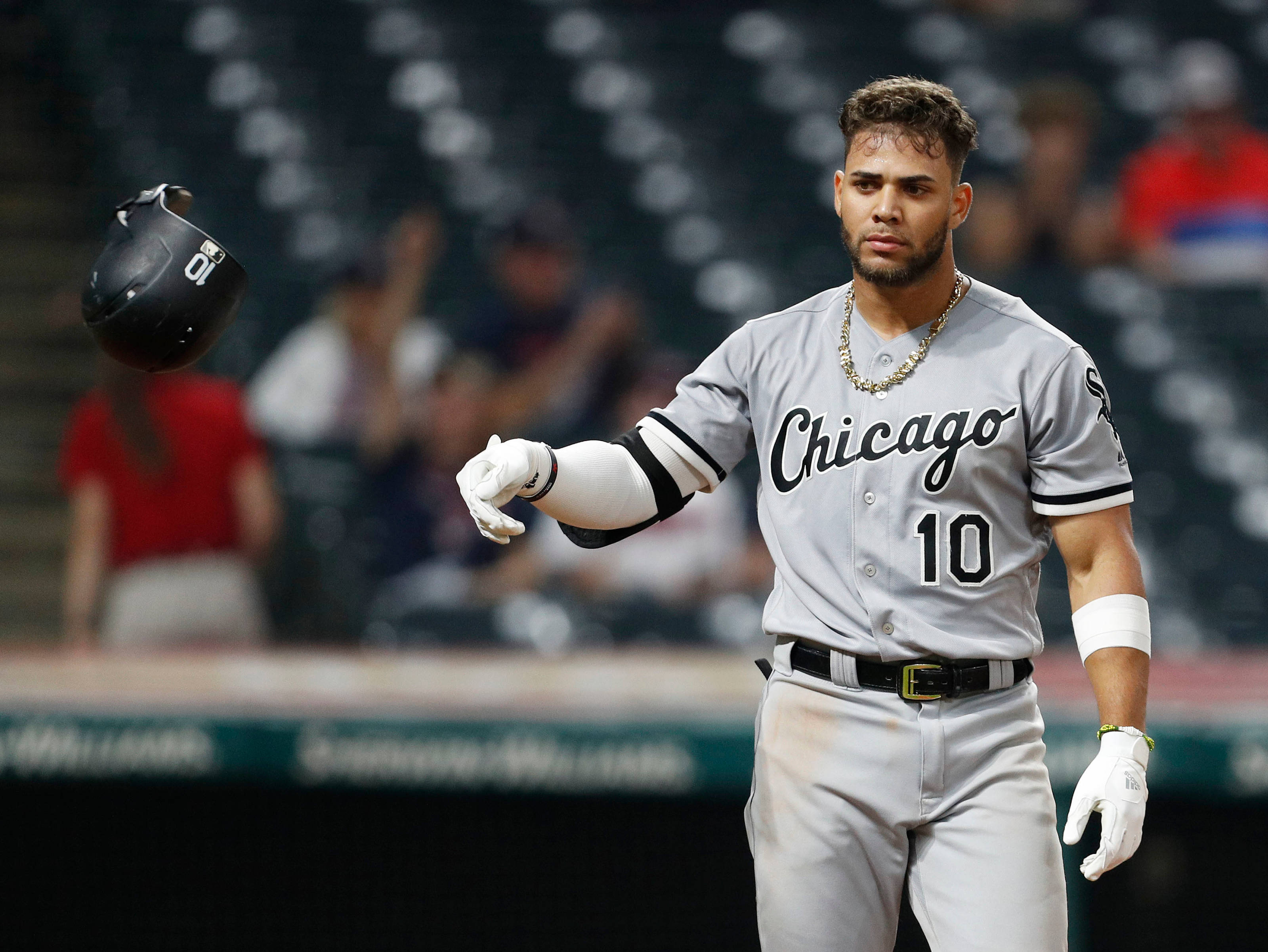 Chicago White Sox 桌布 壁紙 — 一位芝加哥棒球運動員身穿灰色制服，在明亮的燈光下於球場上大步走時拋出頭盔。