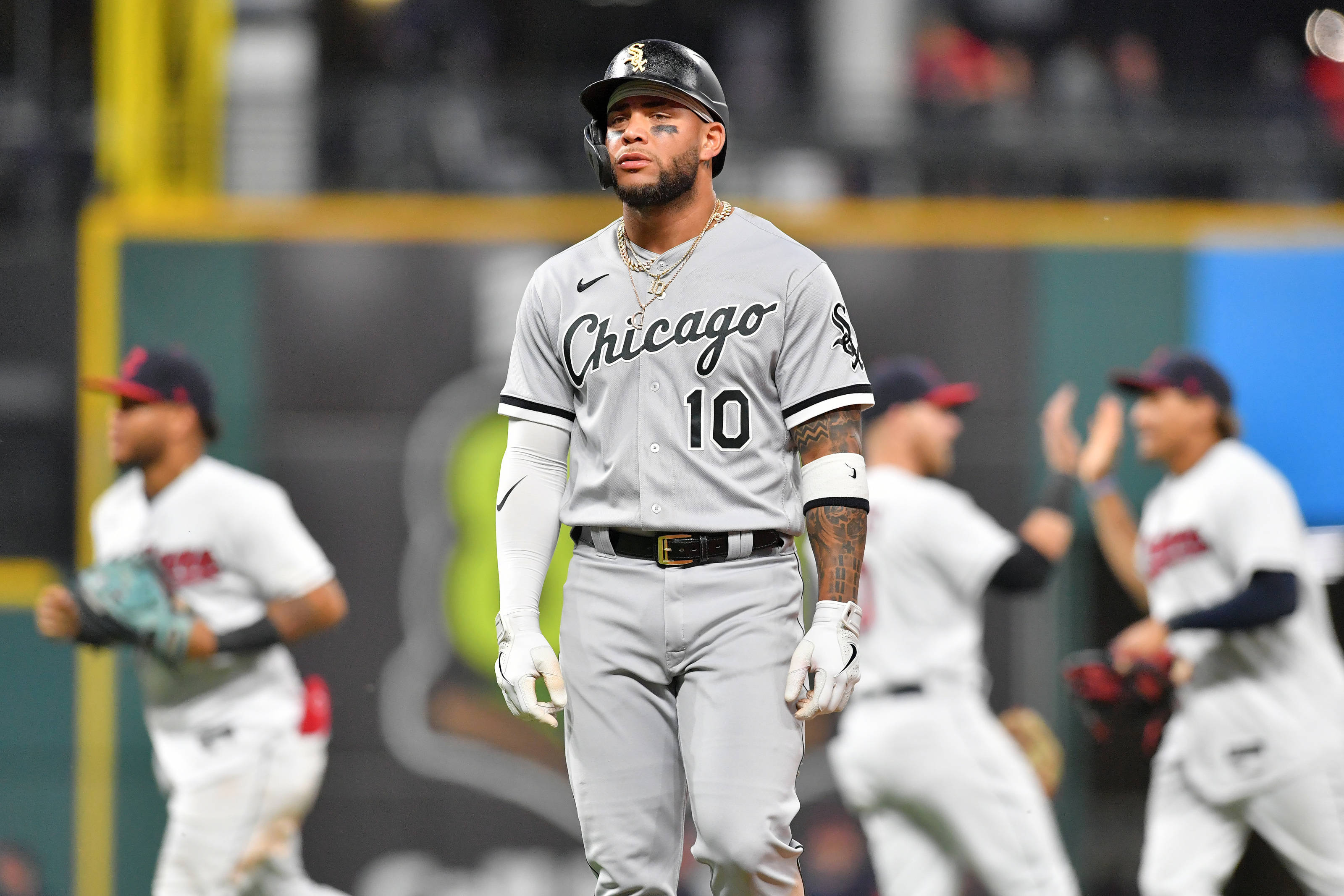 Athlete 桌布 壁紙 — 一位芝加哥棒球選手穿著灰色球衣，在球場上莊嚴地行走，隊友在背景中慶祝。