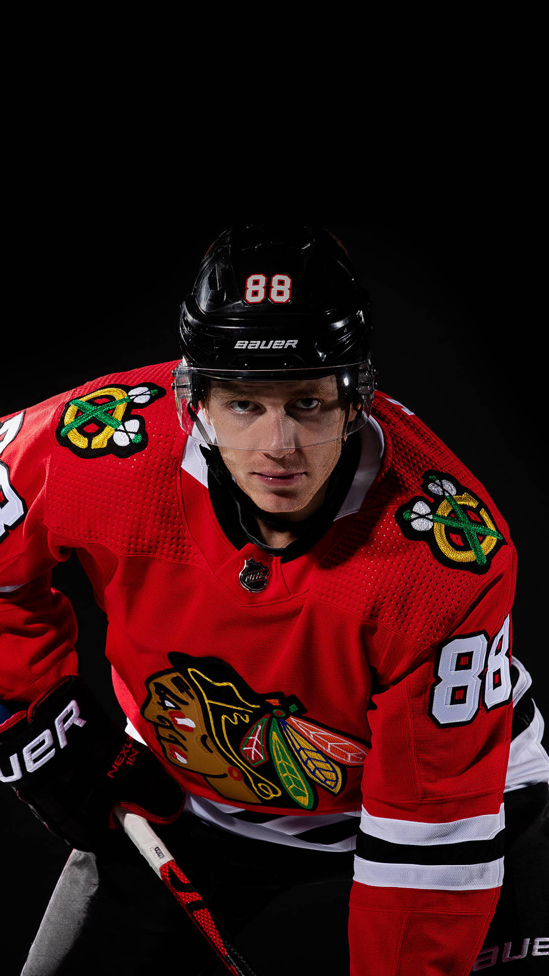 Blackhawks 桌布 壁紙 — 一位芝加哥黑鷹隊的冰球運動員，身穿紅色 88 號球衣，在黑色背景下擺出強烈的姿勢。