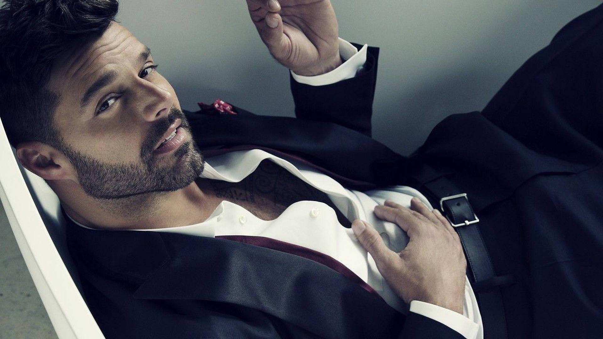 英俊男士身穿黑色西裝靠著，佩戴紅色襟花，可見紋身。 — Michael B Jordan 壁紙