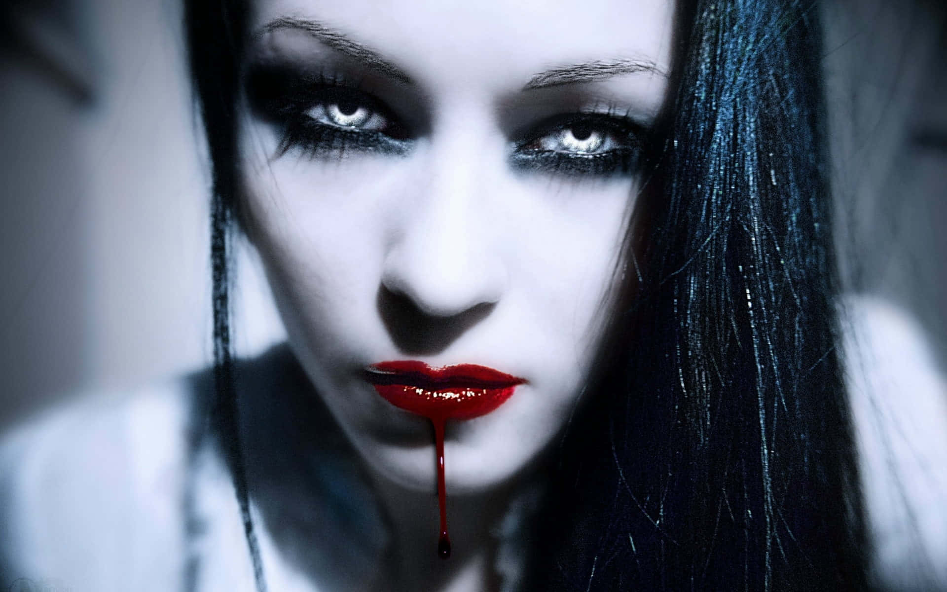 Dark Vampire 桌布 壁紙 — 一位蒼白的女人，深色頭髮和紅唇，一滴血從她嘴裡滴下，令人毛骨悚然的特寫。