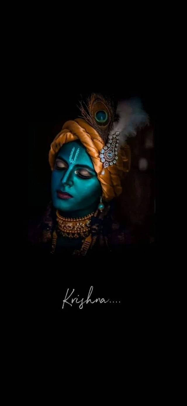 krishna bhagwan 桌布 壁紙 — 一位藍皮膚的神祇，戴著金色王冠和珠寶，在黑暗背景下溫柔地凝視。