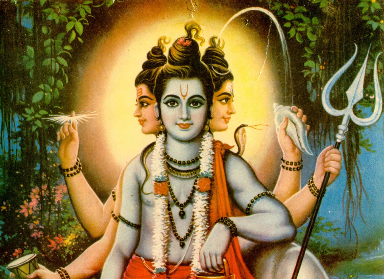 Hindu God 桌布 壁紙 — 一位藍皮膚的神聖三面神祇，在茂密綠葉和光環下手持三叉戟和海螺。