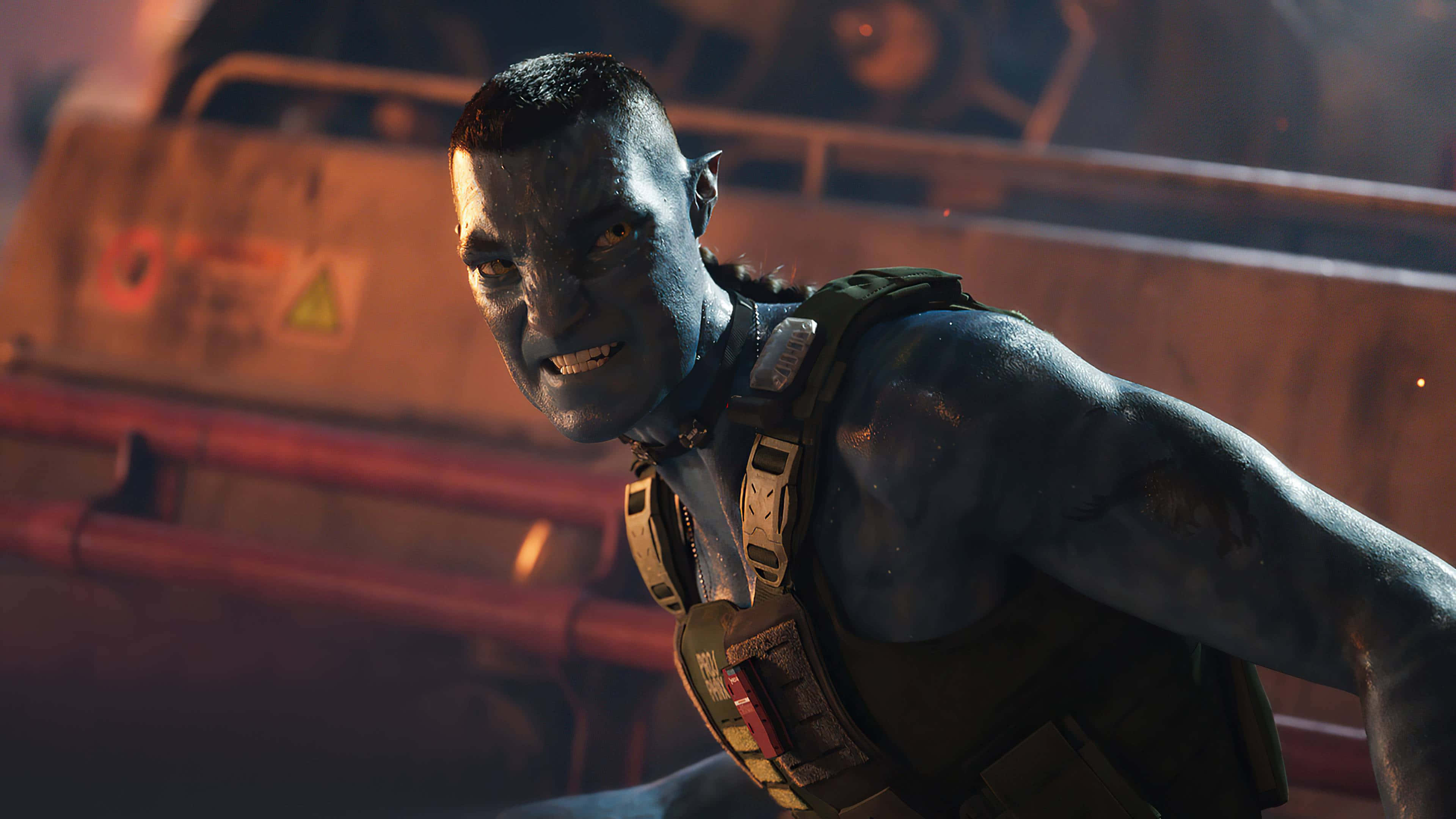 Avatar 2 The Way Of Water 桌布 壁紙 — 一位藍皮膚的納美人戰士，雙眼發光，身穿戰術裝備，在昏暗的工業環境中凝視著。