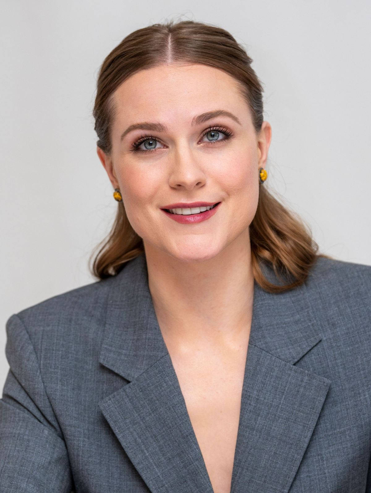 Celebrity 桌布 壁紙 — 一位藍眼睛、棕色頭髮的女性，穿著灰色西裝外套和黃色耳環，背景為純白色。