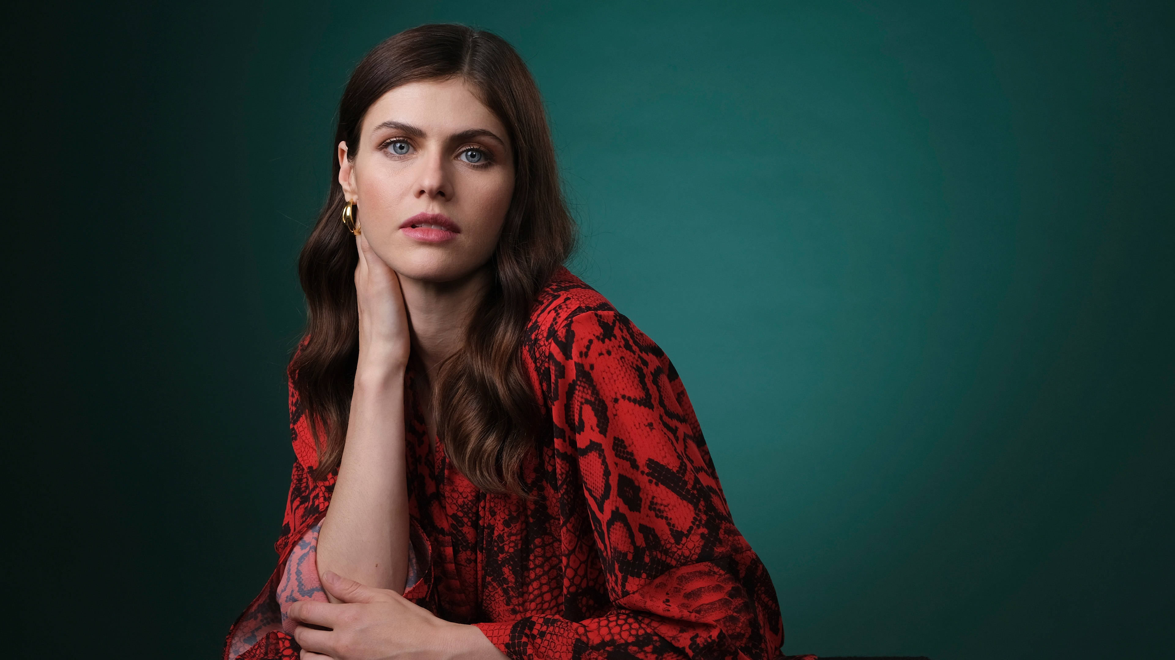 Alexandra Daddario 4K 桌布 壁紙 — 一位藍眼睛、棕色頭髮的女性，身穿紅色蛇紋襯衫，背景是深藍綠色攝影棚。