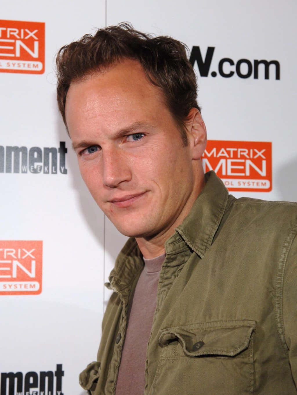 Patrick Wilson 桌布 壁紙 — 一位藍眼睛、棕色頭髮的男子，穿著橄欖綠外套，在Matrix Men活動中微笑。