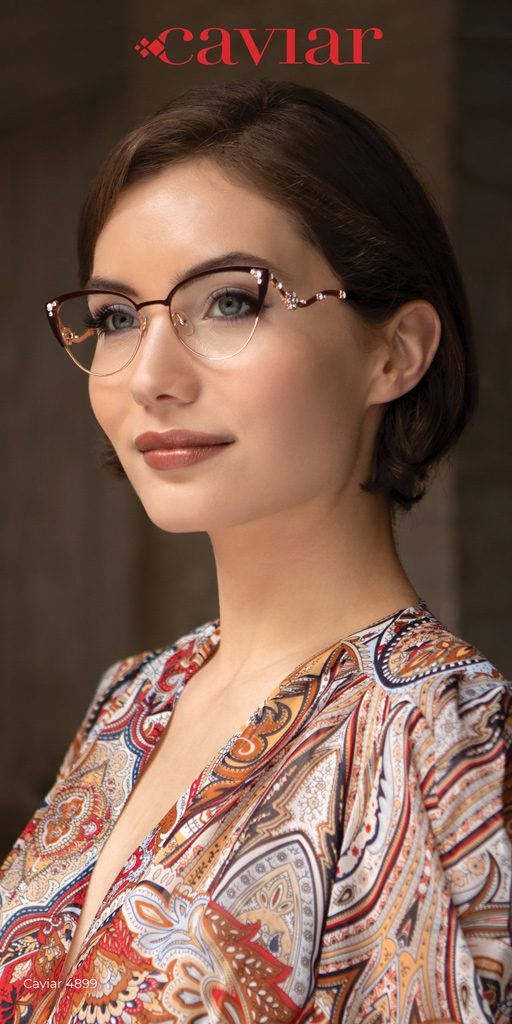 glasses 桌布 壁紙 — 一位藍眼睛、深色頭髮的女性，在柔和的背景下戴著華麗的眼鏡和色彩繽紛的佩斯利圖案襯衫。