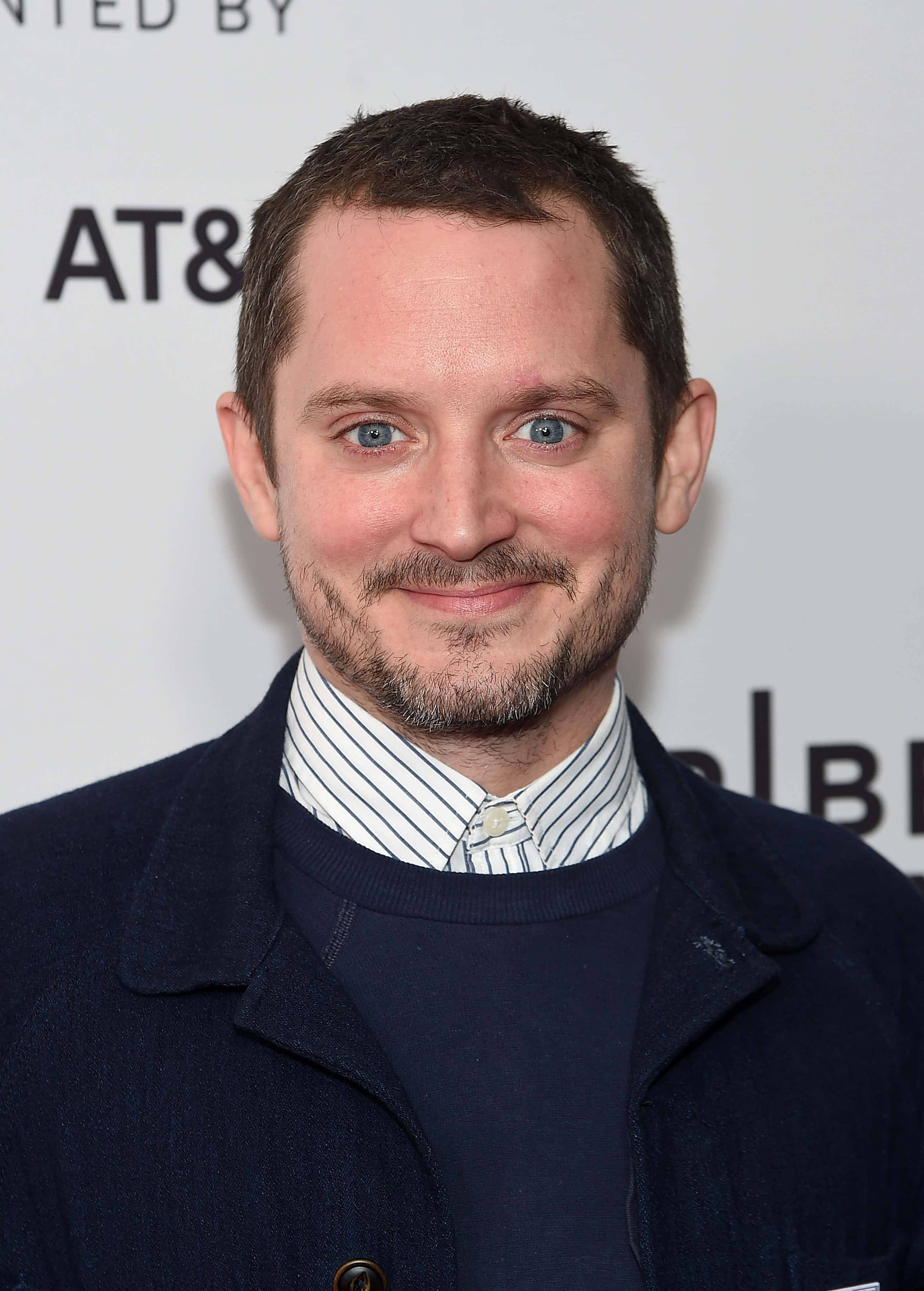 Celebrity 桌布 壁紙 — 一位藍眼睛、留鬍鬚的男子，在活動中穿著海軍藍外套配條紋襯衫，溫暖地微笑。