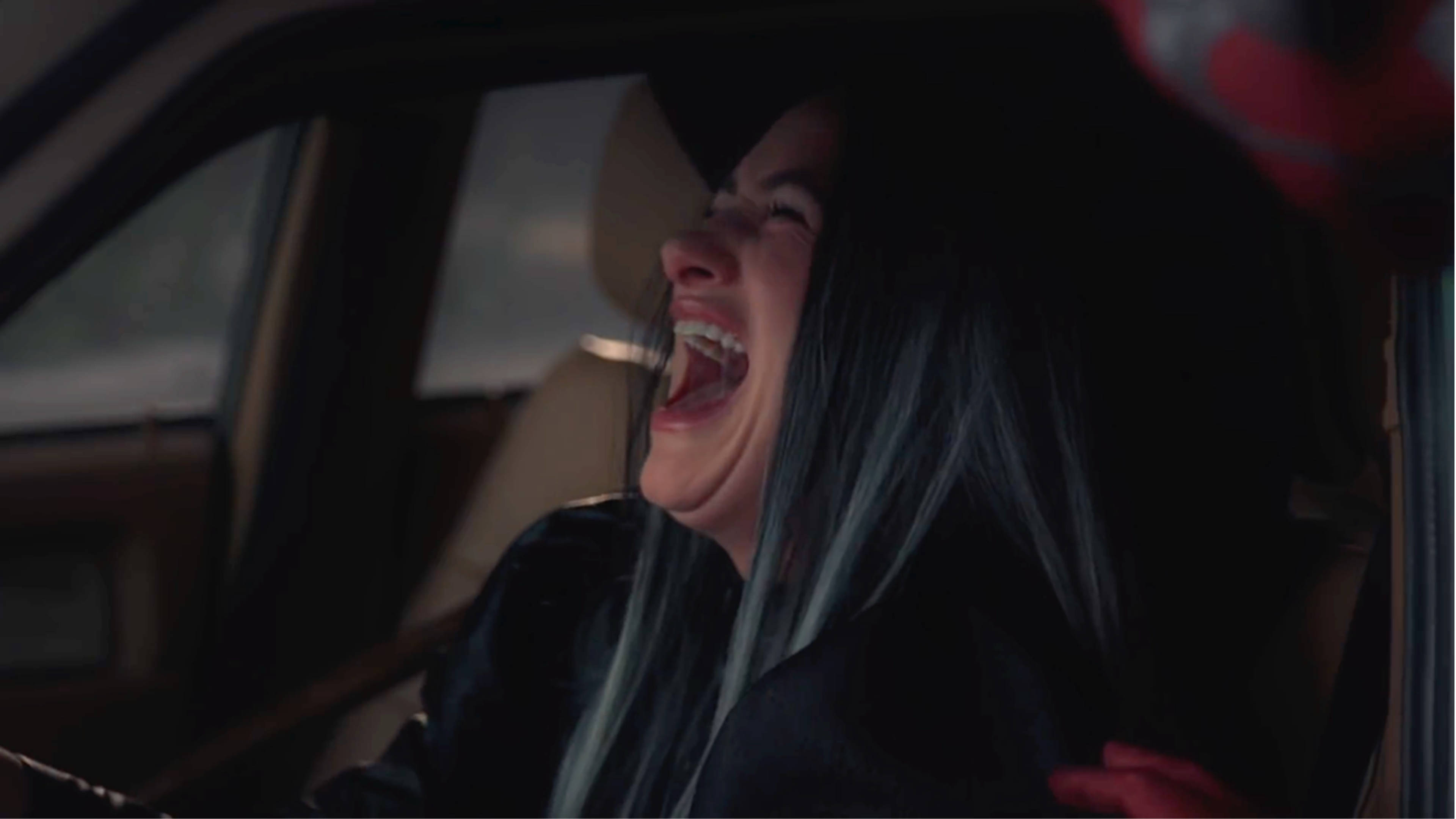 Agatha 桌布 壁紙 — 一位藍髮年輕女性在昏暗燈光下坐在車內，開懷大笑。