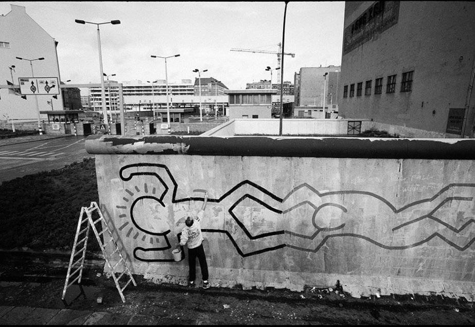 Black And White Graffiti 桌布 壁紙 — 一位藝術家在都市環境的混凝土牆上繪製太陽和抽象圖案的粗黑線條畫。