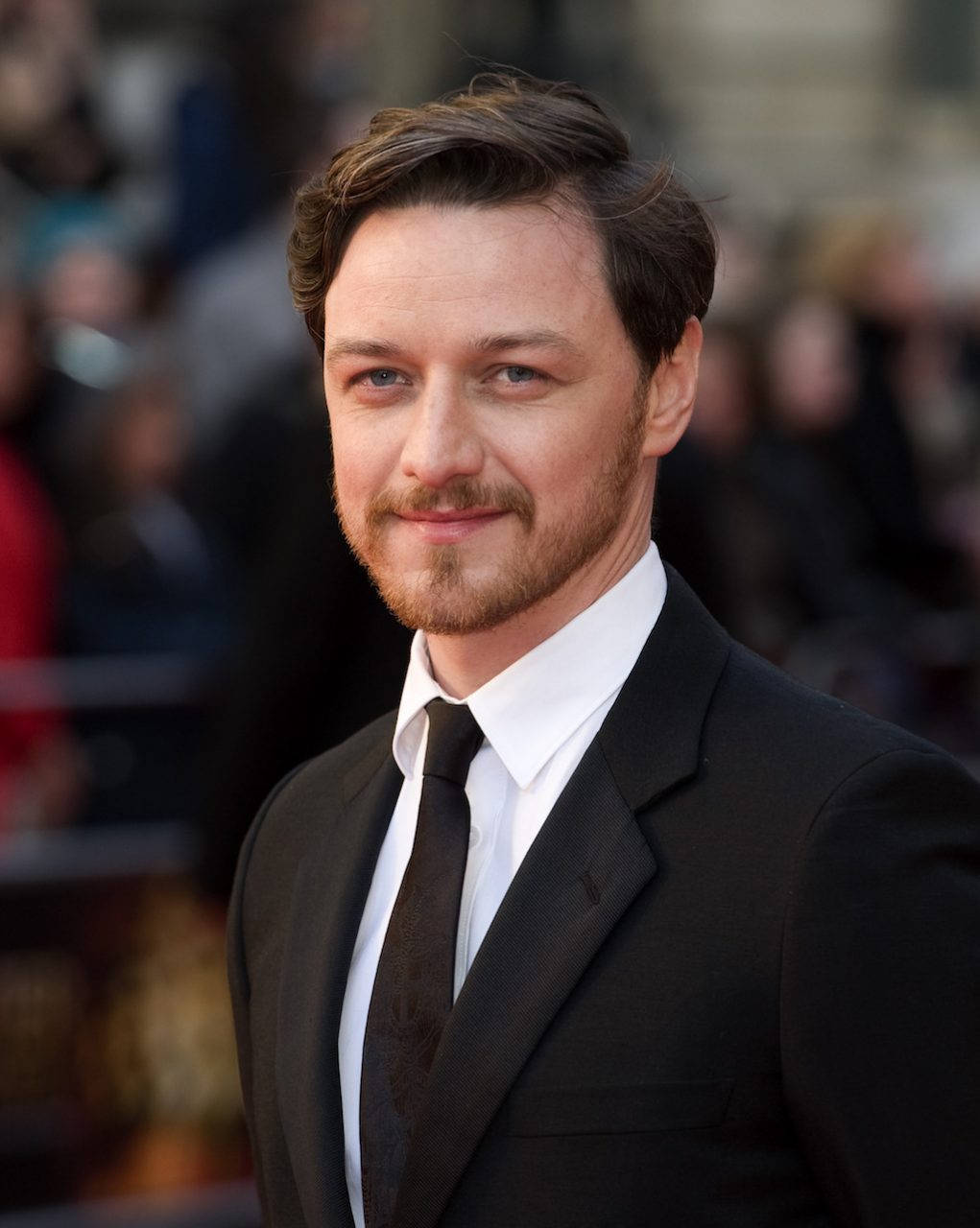 Celebrity 桌布 壁紙 — 一位衣著講究、笑容溫暖、頭髮整齊的男士自信地站在紅地毯上，身後是模糊的人群。