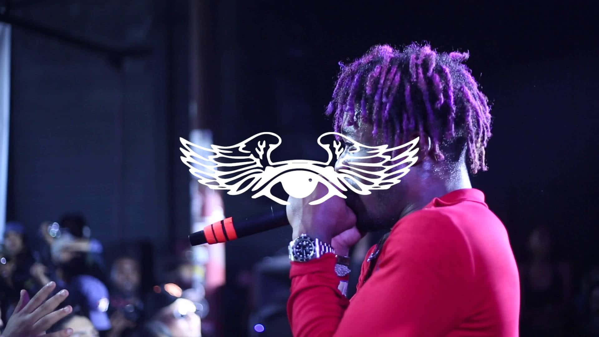 Lil Uzi Vert 桌布 壁紙 — 一位表演者留著紫色辮子，在舞台燈光下對著麥克風唱歌，並帶有發光的翼眼標誌疊加。