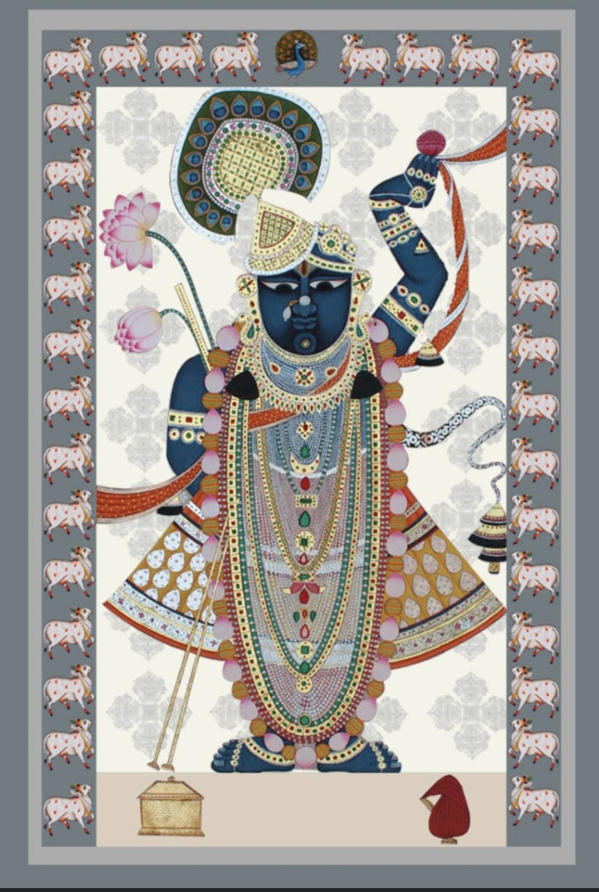 Shrinathji 桌布 壁紙 — 一位裝飾華麗的藍色神祇，多臂手持象徵物品，背景為帶有重複山羊圖案和花卉點綴的圖案邊框。