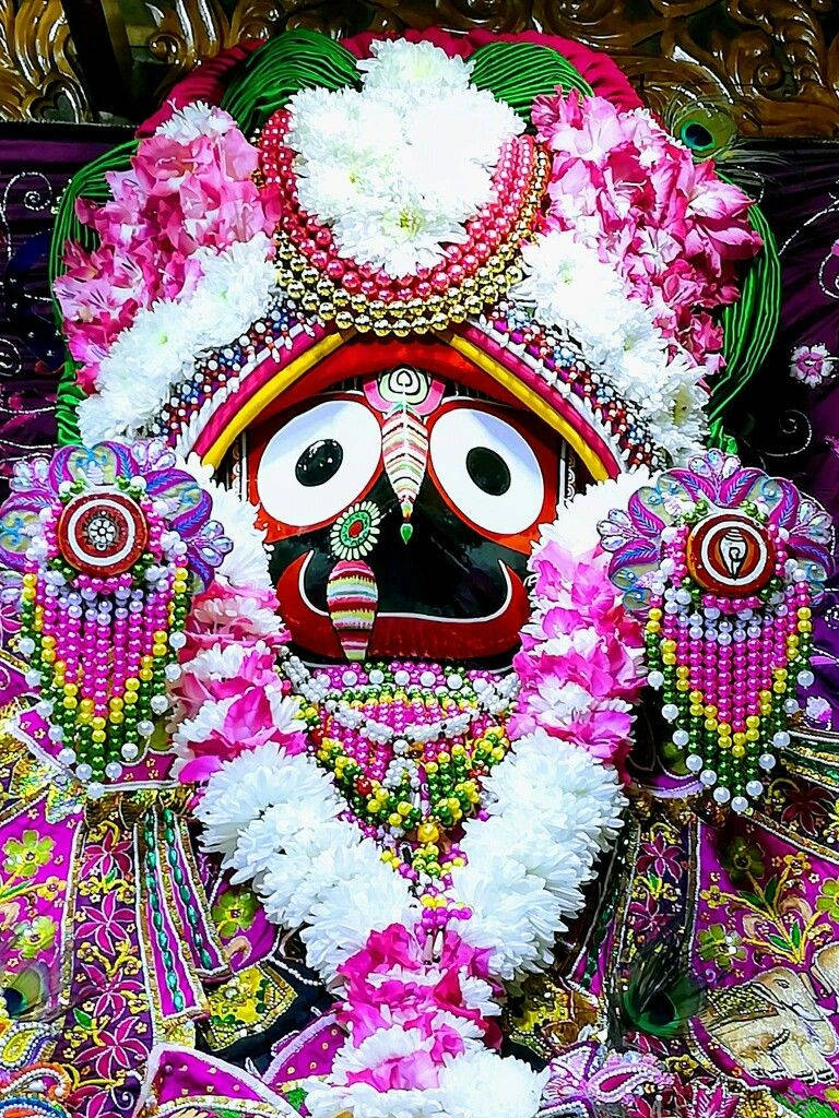 Jagannath 桌布 壁紙 — 一位裝飾鮮豔的印度教神祇，有著白色大眼睛和紅色臉龐，周圍環繞著粉紅色和白色的花朵以及色彩繽紛的珠子。
