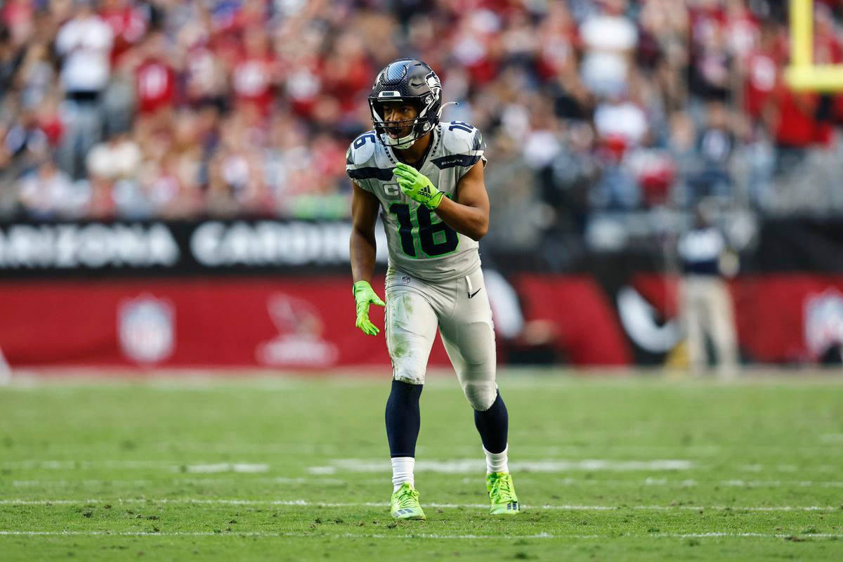 Seattle Seahawks 桌布 壁紙 — 一位西雅圖海鷹隊的18號美式足球員站在綠色球場上，背景是模糊的人群。